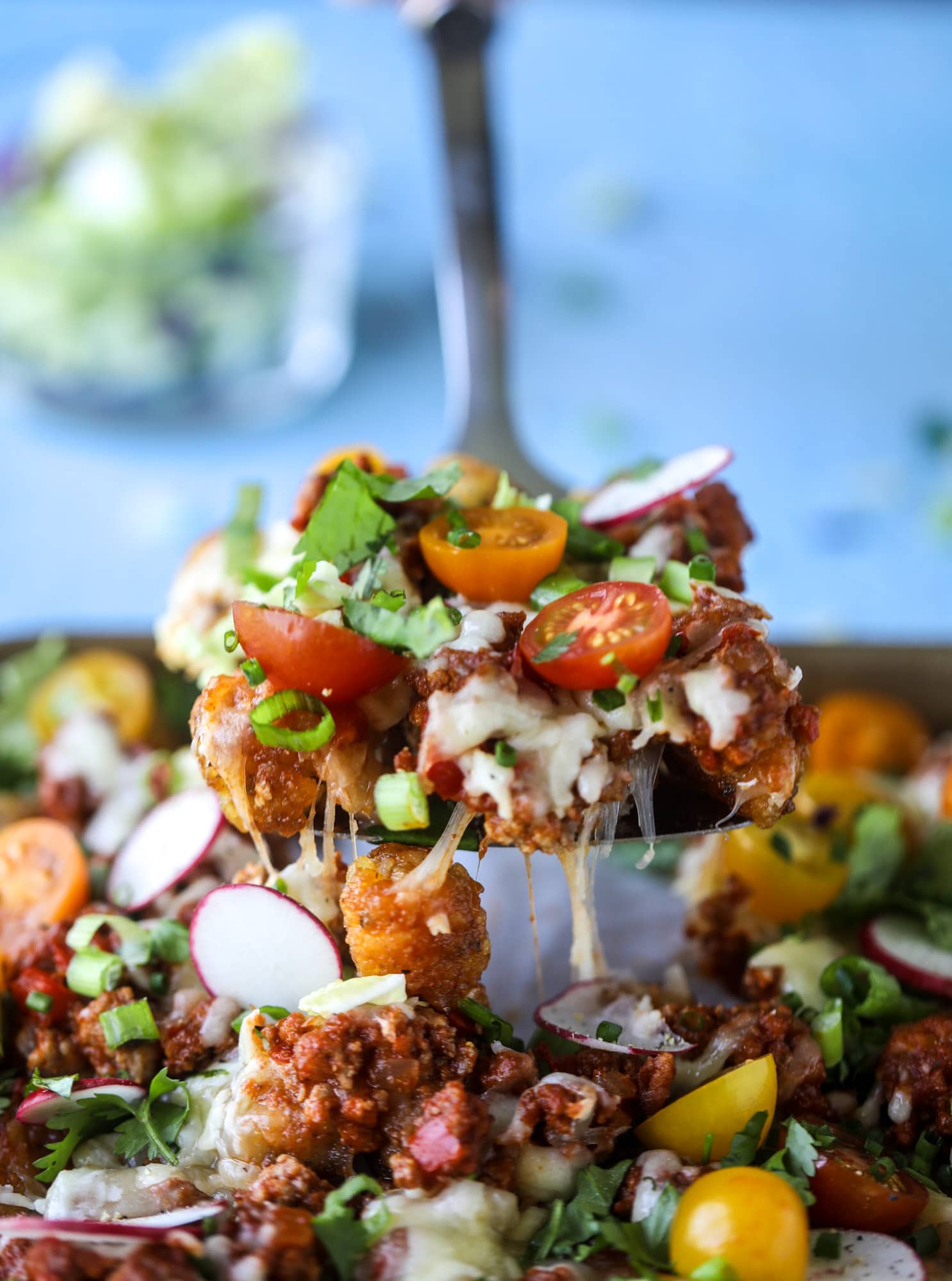 These tater tot nachos, otherwise known as totchos, are so delicious! They are cheesy and topped with a tangy, homemade sloppy joe mixture. Melted cheese, fresh tomatoes, scallions and chives come together for the best party food. I howsweeteats.com #totchos #tater #tot #nachos #sloppy #joes