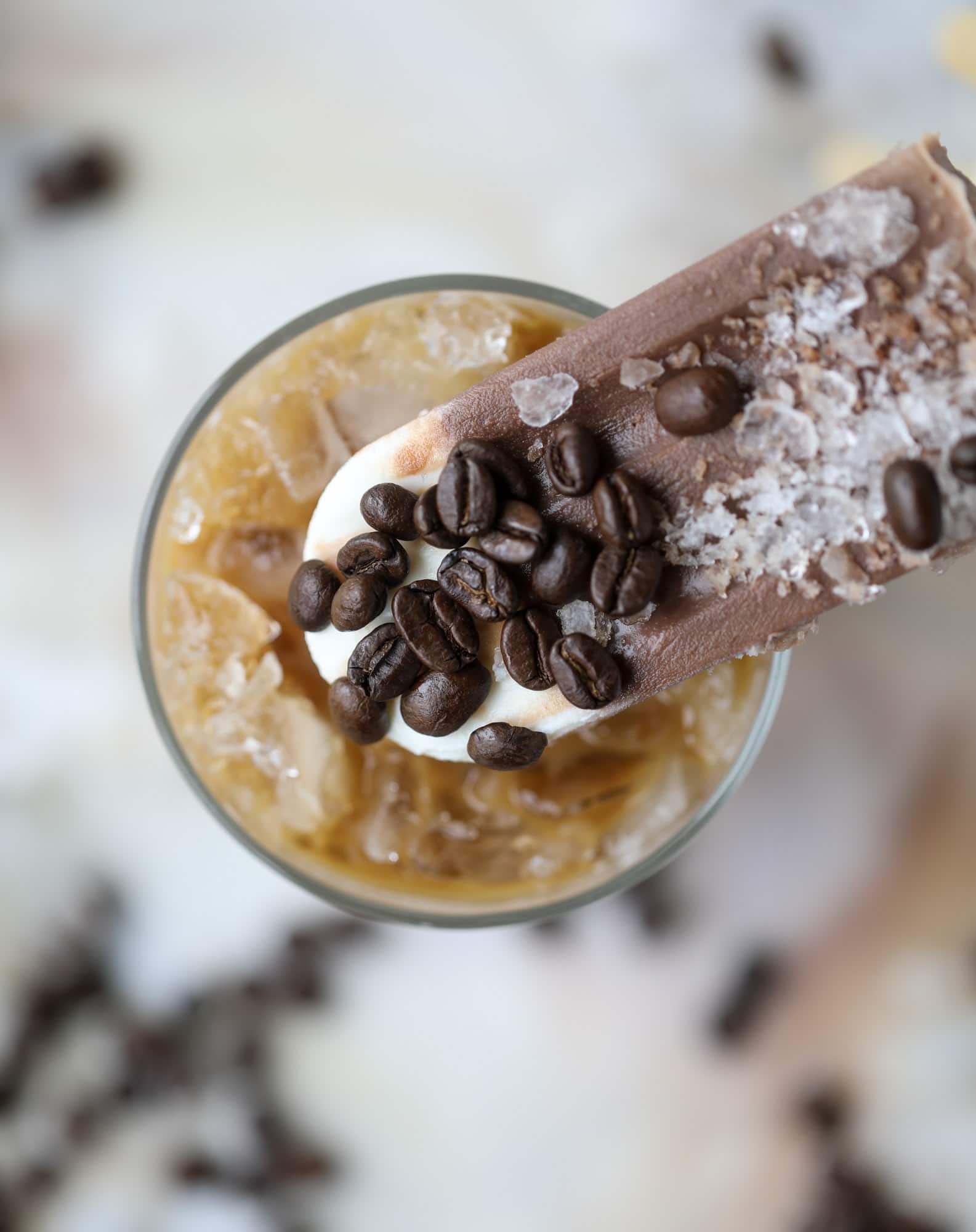 These fudgesicles are made with cold brew and dutch process cocoa for the most fun grown-up popsicle that can also deliver a little caffeine jolt. Topped with vanilla bean sweet cream, these are just like an iced latte in a pop! Serve as a treat or a snack! I howsweeteats.com #coldbrew #coffee #sweet #cream #popsicle #fudgesicle