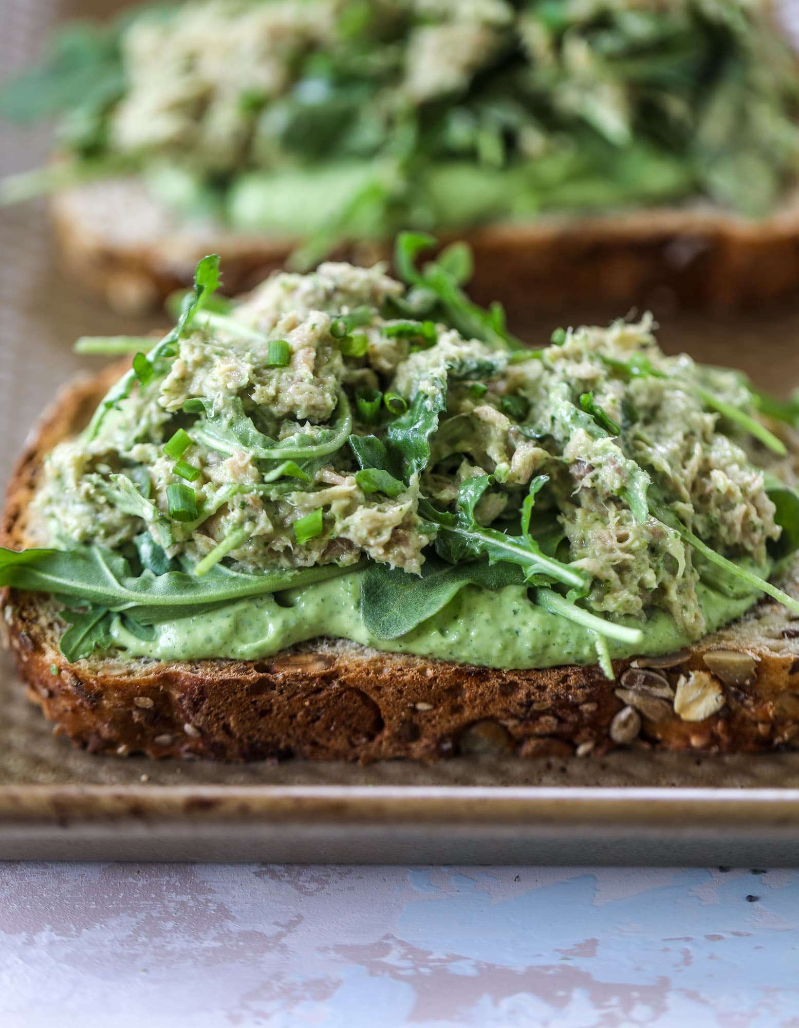 These green green tuna melt tartines are a lunch dream come true! The green goddess dressing is full of avocado, greek yogurt, spinach and fresh herbs. Paired with the tuna, whole grain toast and melty cheese, it's incredibly delicious and a super easy lunch! I howsweeteats.com #green #goddess #tune #salad #melts
