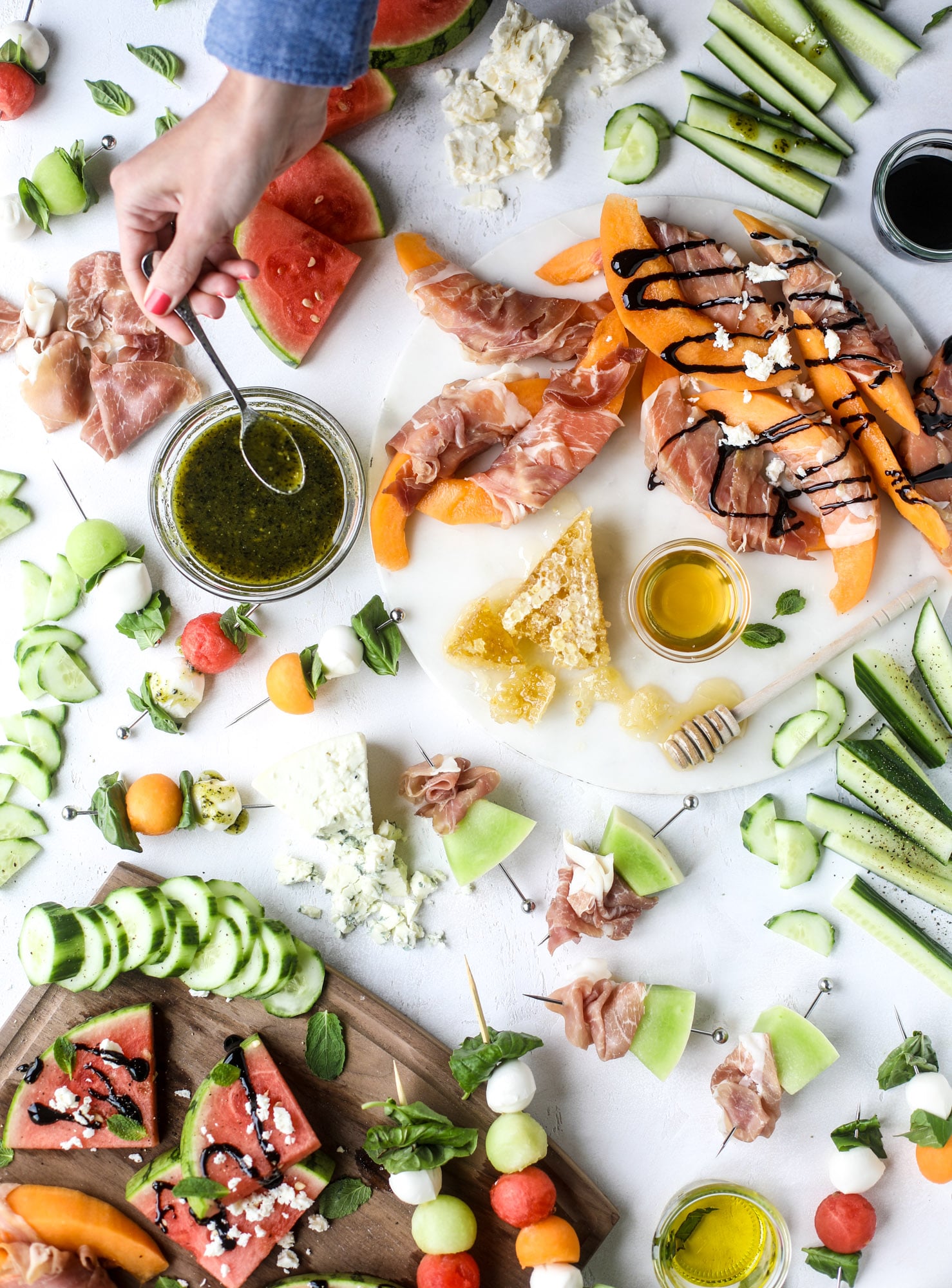 Create a melon summer snacking board with watermelon, cantaloupe, cucumber and honeydew. Drizzled with balsalmic, pesto, fresh herbs and paired with prosciutto and marinated mozzarella. I howsweeteats.com #melon #summer #snack #cheese #board #watermelon