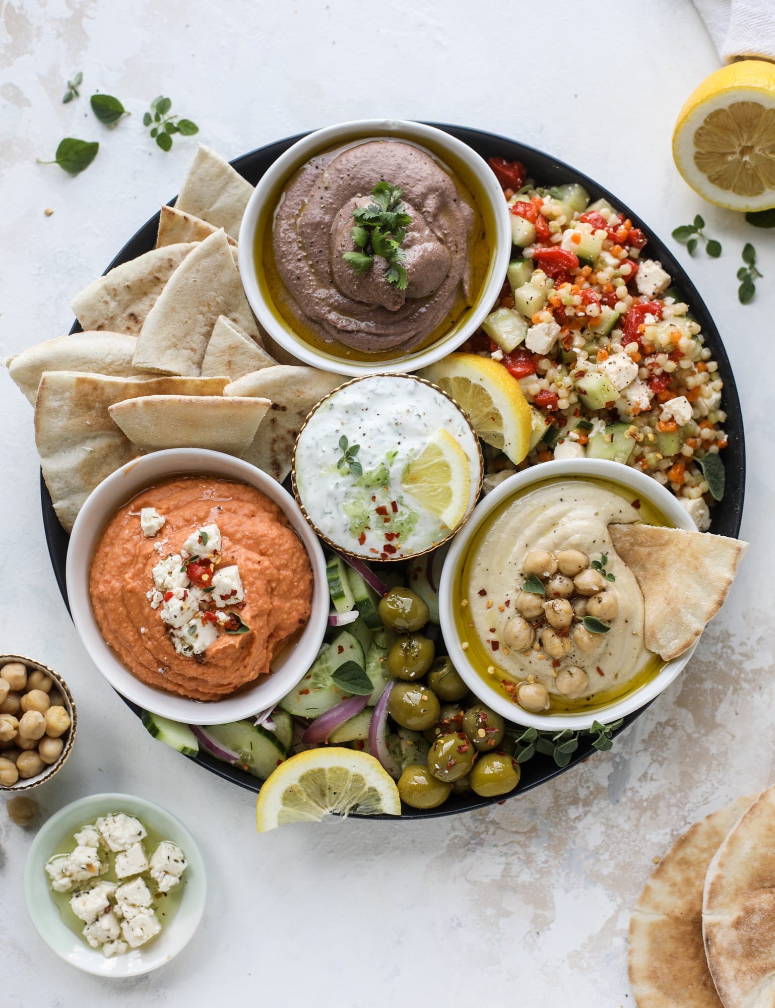 Here you can find out how to make the perfect hummus platter! This trio includes caramelized onion hummus, smoky black bean hummus and roasted red pepper white bean hummus, along with a couscous salad and quick tzatziki! I howsweeteats.com #hummus #platter #appetizer #snack #chickpeas #healthy #blackbeans #yogurt #tzatziki