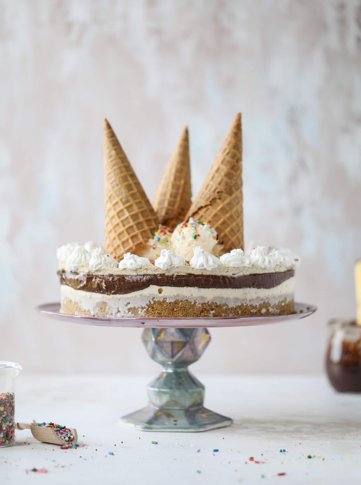 This peanut butter fudge ice cream cake is absolutely insane and perfect for summer! A sweet and savory pretzel crust, vanilla ice cream, homemade hot fudge and a peanut butter whipped cream layer take it to the next LEVEL. Delicious! I howsweeteats.com #icecream #cake #peanutbutter #chocolate #pretzel