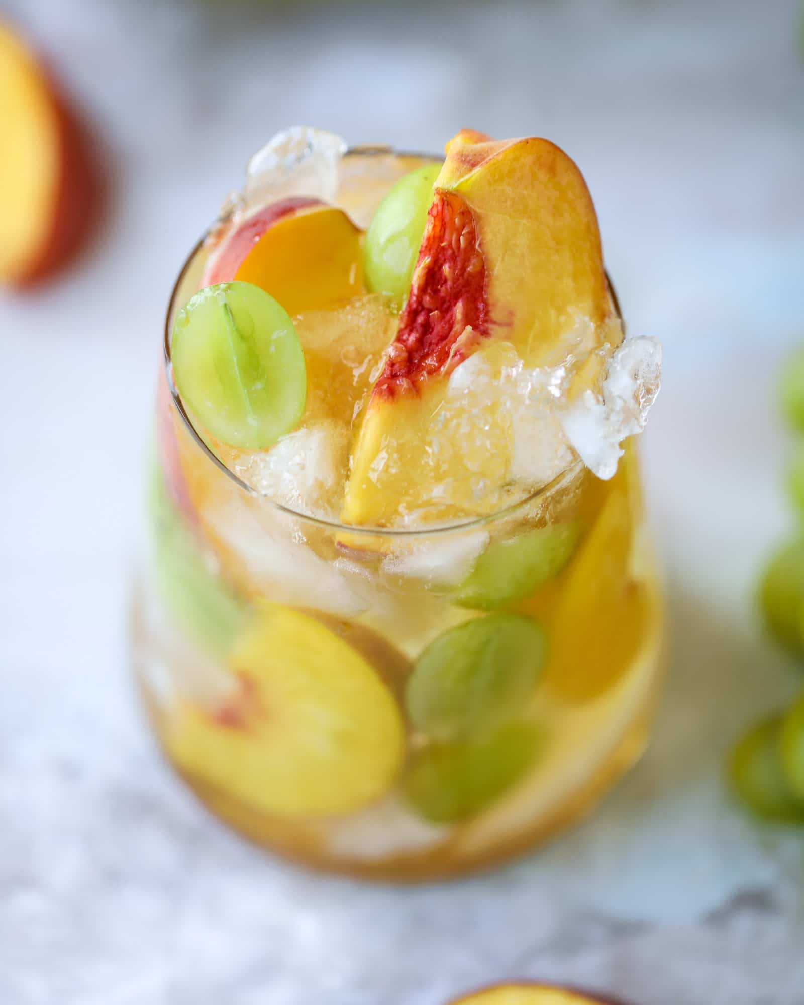 This pinot grigio sangria is absolutely perfect for summer, complete with peach nectar, fresh and frozen peach slices, brandy and bubbles! Frozen green grapes add some chill without watering down the drink. It's perfect! I howsweeteats.com #pinot #grigio #peach #sangria #cocktails #punch #summer #wine
