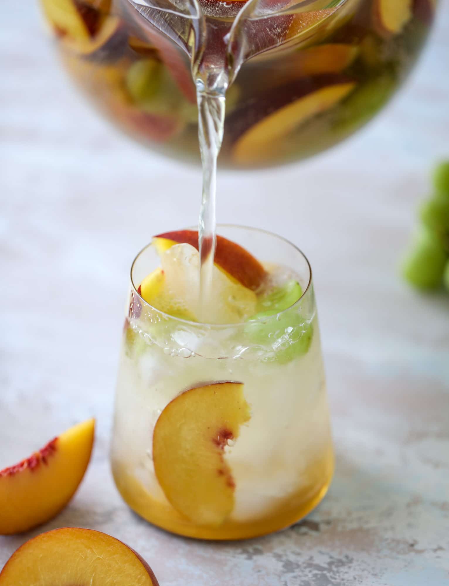 This pinot grigio sangria is absolutely perfect for summer, complete with peach nectar, fresh and frozen peach slices, brandy and bubbles! Frozen green grapes add some chill without watering down the drink. It's perfect! I howsweeteats.com #pinot #grigio #peach #sangria #cocktails #punch #summer #wine