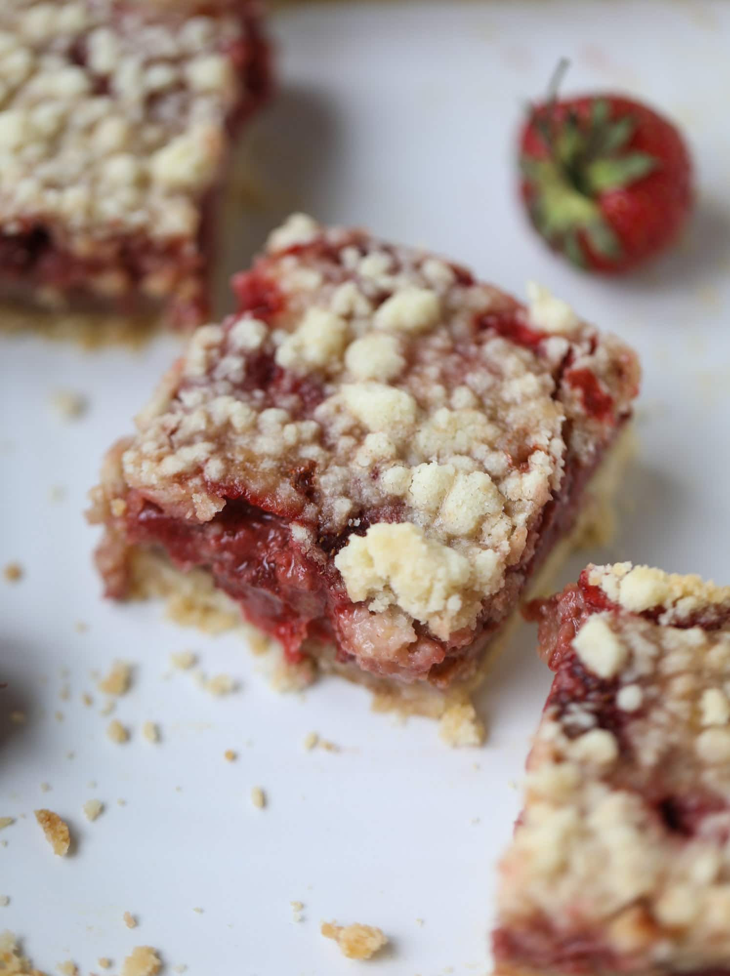 These strawberry cobbler bars are super delicious and perfect for a crowd! Made with juicy fresh strawberries, they start with a shortbread crust and end with a crumbly topping with a warm and delicious fruity filling. Huge hit! I howsweeteats.com #strawberry #cobbler #bars