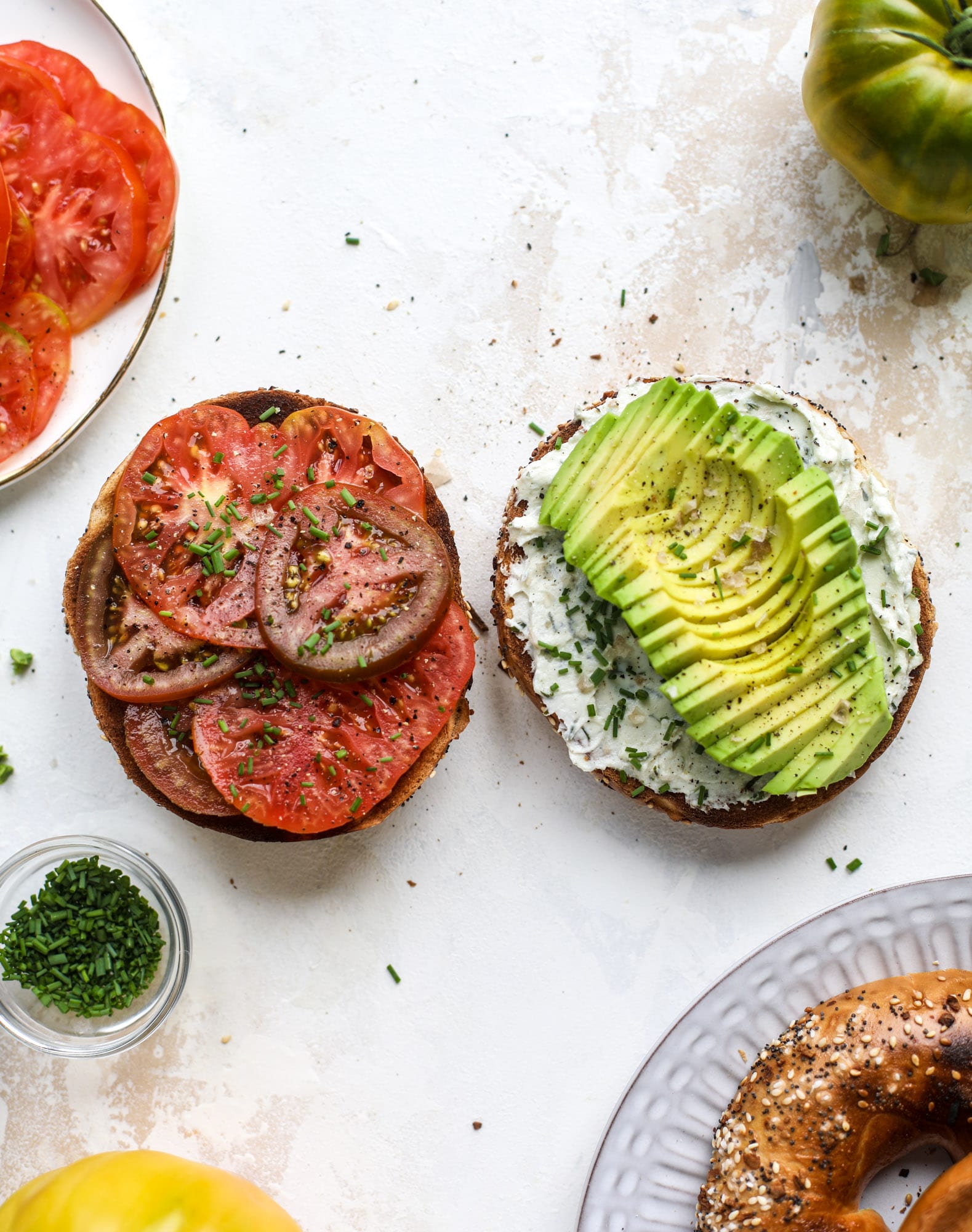 These avocado tomato sandwiches are the perfect lunch! Complete with veggie cream cheese, smoked sea salt, fresh chives and microgreens, the sliced avocado and heirloom tomatoes are sandwiched on an everything bagel for a flavor explosion. I howsweeteats.com #avocado #tomato #sandwich #healthy #lunch