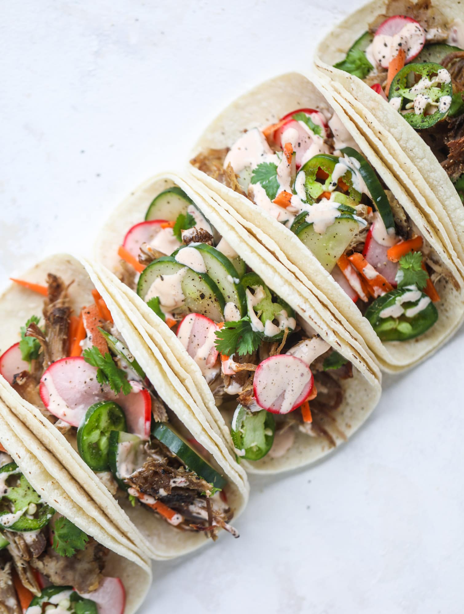 These bahn mi tacos are the perfect twist on the classic sandwich! Juicy pulled pork, pickled veggies, a tangy crema and loads of flavor. Bahn mi tacos are a delish weeknight meal or also work great if you have pork leftovers! I howsweeteats.com #bahn #mi #tacos #pork #dinner