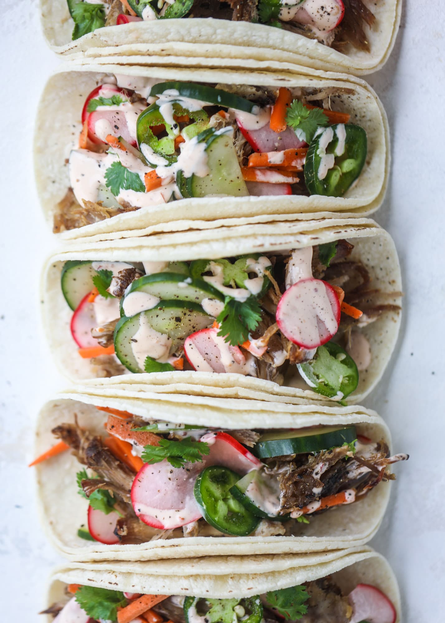These bahn mi tacos are the perfect twist on the classic sandwich! Juicy pulled pork, pickled veggies, a tangy crema and loads of flavor. Bahn mi tacos are a delish weeknight meal or also work great if you have pork leftovers! I howsweeteats.com #bahn #mi #tacos #pork #dinner