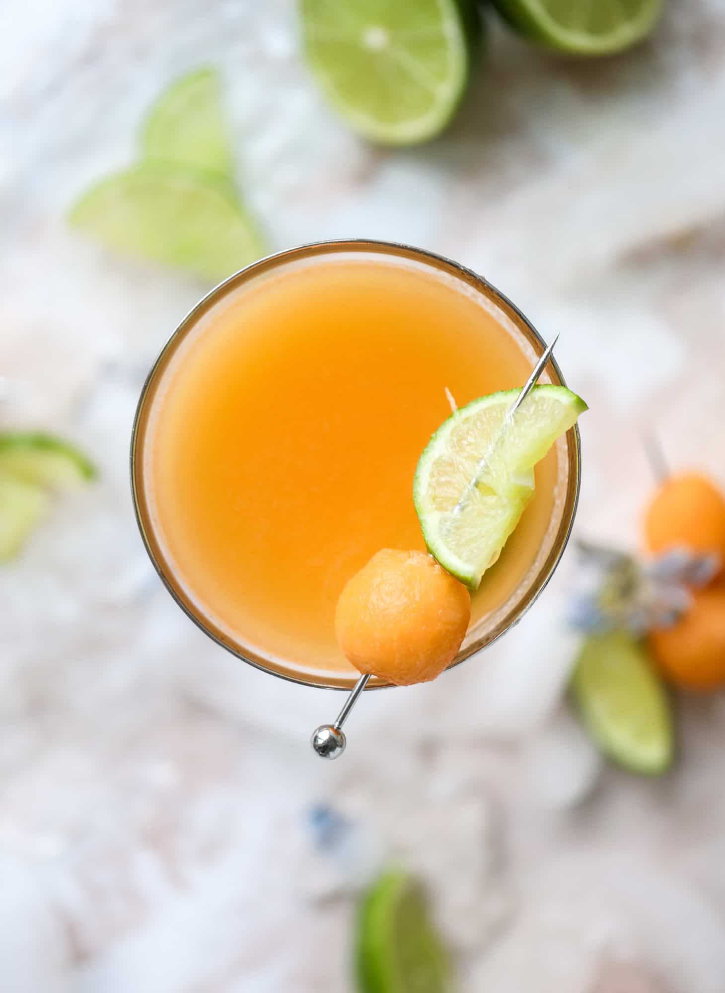This cantaloupe daiquiri is the perfect way to celebrate summer! Freshly juiced melon, lime juice, rum and maraschino cherries - it's refreshing and cool and a fantastic cocktail to have during happy hour! Isn't the color amazing too?! I howsweeteats.com #cantaloupe #cocktail #daiquiri #lime #rum #summer