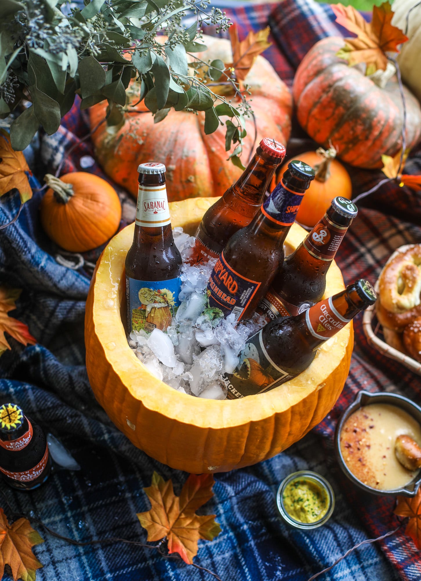 This is the cutest way ever to serve the best pumpkin beer! If you do a pumpkin beer party of a pumpkin beer tasting, this pumpkin cooler is an adorable (and easy!) way to make things festive. Kick it up with a hot pretzel bar and lots of dipping sauce too! I howsweeteats.com #pumpkin #beer #cooler #softpretzel #fall #cheese