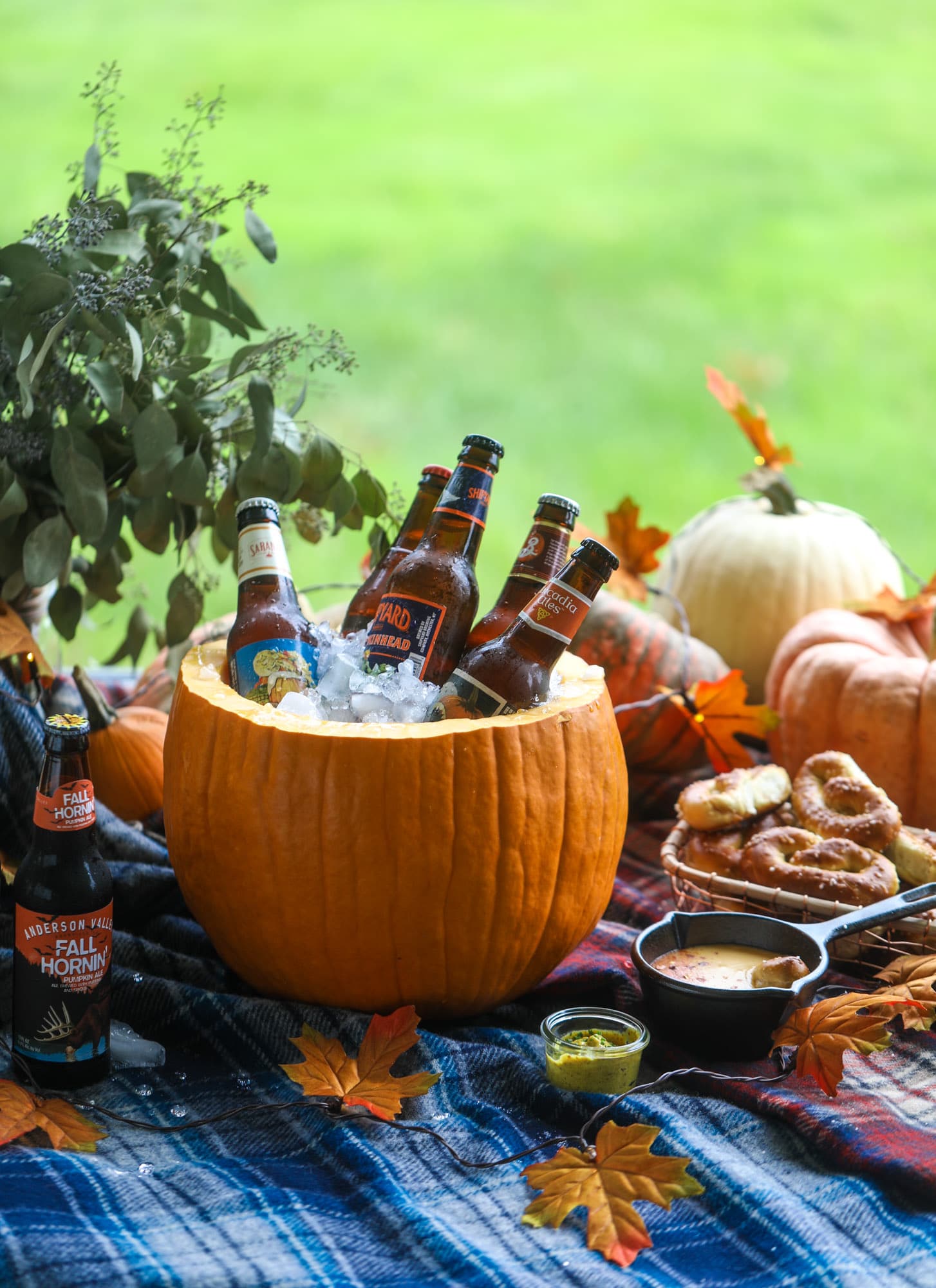This is the cutest way ever to serve the best pumpkin beer! If you do a pumpkin beer party of a pumpkin beer tasting, this pumpkin cooler is an adorable (and easy!) way to make things festive. Kick it up with a hot pretzel bar and lots of dipping sauce too! I howsweeteats.com #pumpkin #beer #cooler #softpretzel #fall #cheese