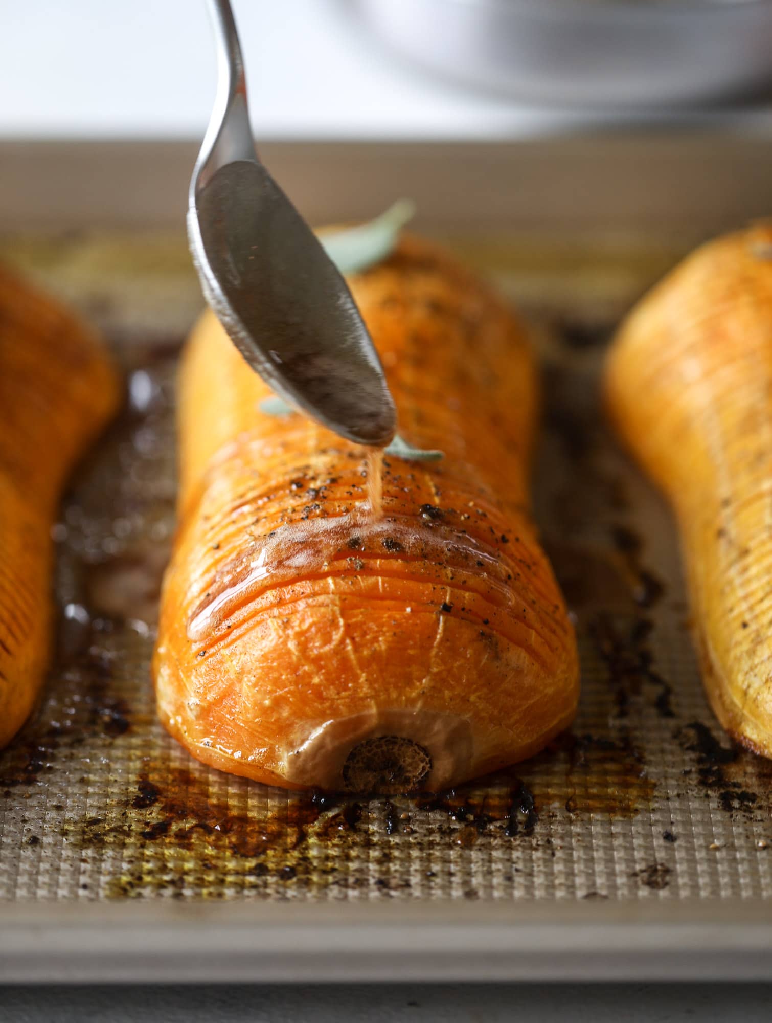 This hasselback butternut squash is perfect for Thanksgiving - and you can easily make it two ways! We have a maple pecan hassleback butternut squash and a brown butter sage hasselback butternut squash. Delicious! I howsweeteats.com #hasselback #butternutsquash