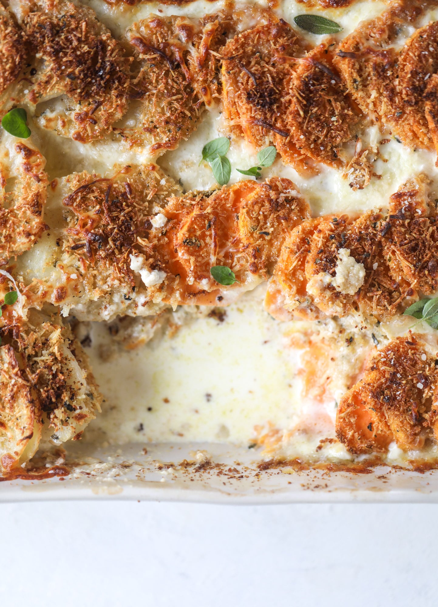 These scalloped potatoes are a cheese lover's dream. Sharp asiago and cream envelops idaho and sweet potatoes in these scalloped potatoes to please everyone! The crunchy asiago topping is irresistible. I howsweeteats.com #scalloped #potatoes