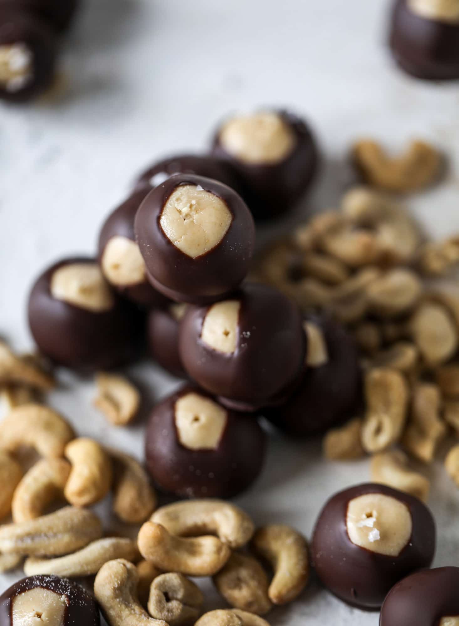 These cashew butter buckeyes are a fun and modern twist on the traditional buckeye recipe! Creamy cashew butter makes a delicious, rich dough and then it's coated in chocolate and sprinkled with sea salt. Delicious! I howsweeteats.com #cashewbutter #buckeyes
