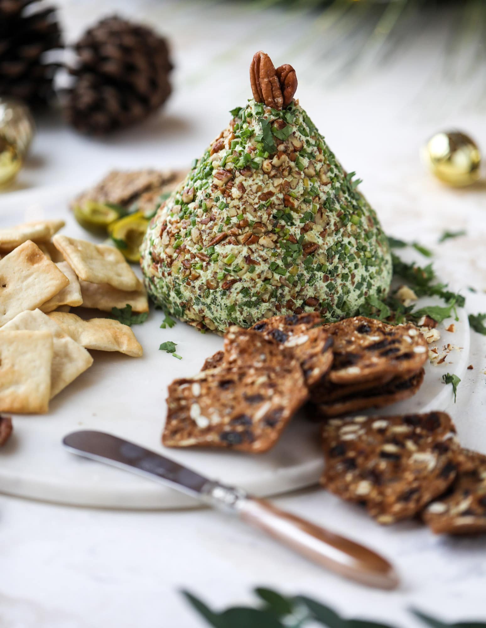 This green goddess cheese ball is the perfect party snack! You can make it ahead of time and shape it into a cute tree for a festive look. Serve it with crispy crackers and pita chips! I howsweeteats.com #greengoddess #cheeseball