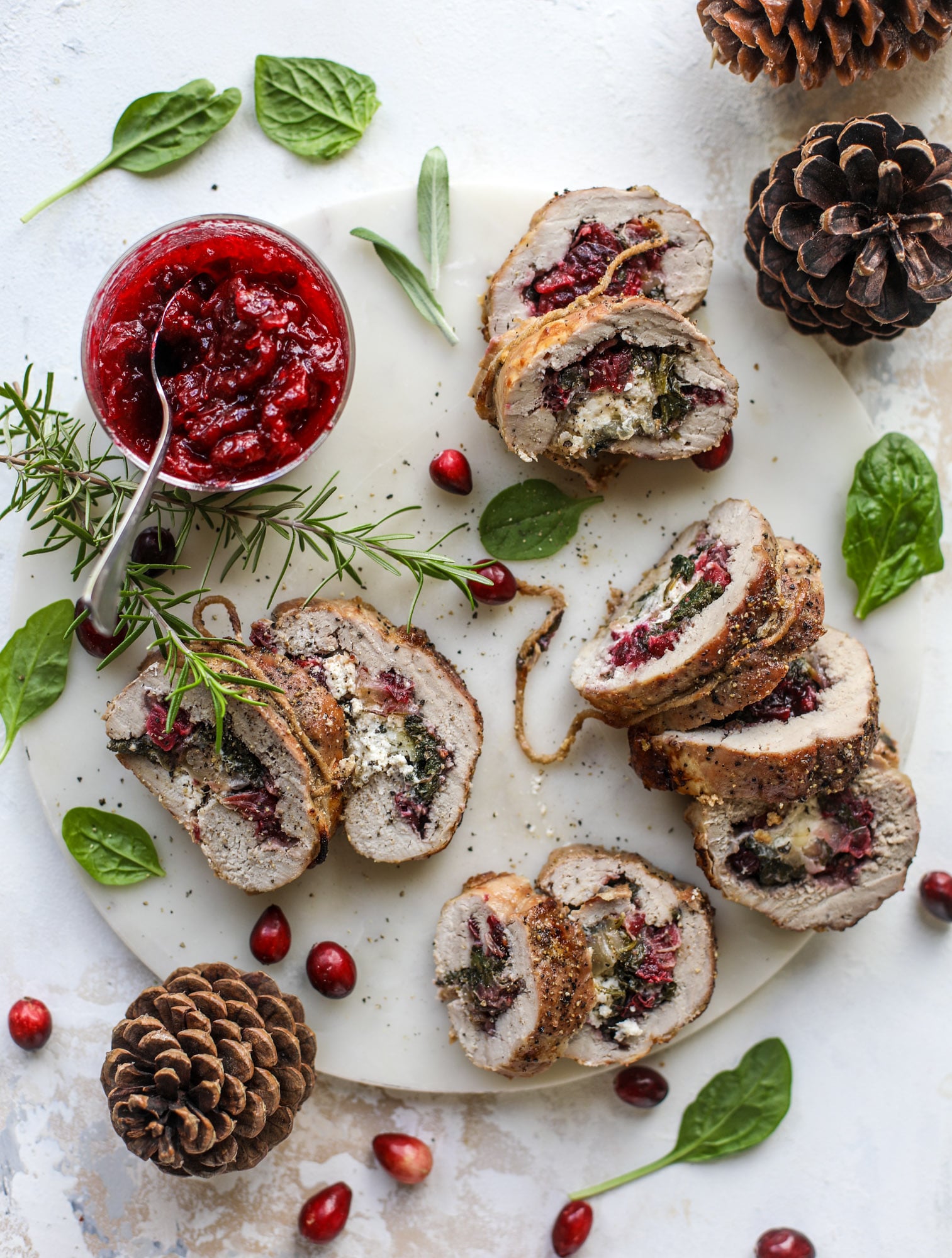 This holiday stuffed pork tenderloin is filled with caramelized onion, fresh cranberry sauce, goat cheese and fresh spinach. It's a show stopped and super delicious, along with being fairly simple to make! I howsweeteats.com #stuffed #porktenderloin