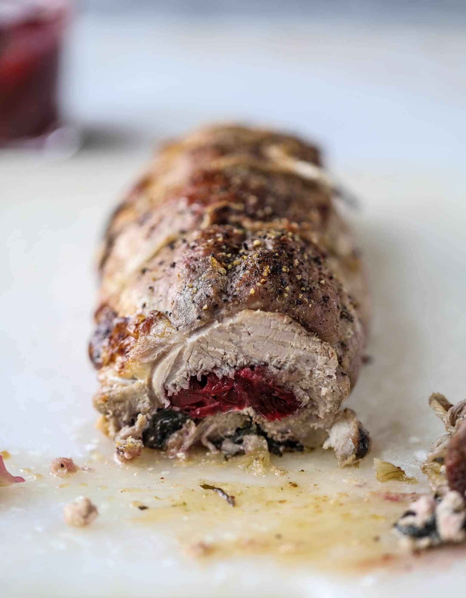 This holiday stuffed pork tenderloin is filled with caramelized onion, fresh cranberry sauce, goat cheese and fresh spinach. It's a show stopped and super delicious, along with being fairly simple to make! I howsweeteats.com #stuffed #porktenderloin
