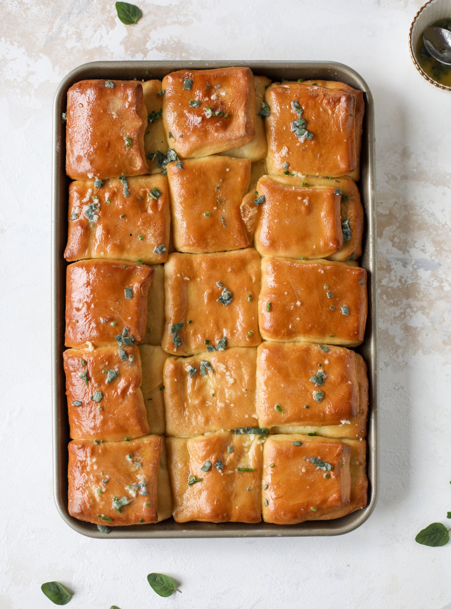 Garlic herb parker house rolls are full of incredibly buttery flavor! They are brushed with a garlic herb butter and are super fluffy, soft and tender. Perfect for Thanksgiving or the holidays and you can make the dough a bit ahead of time! I howsweeteats.com #parkerhouse #rolls