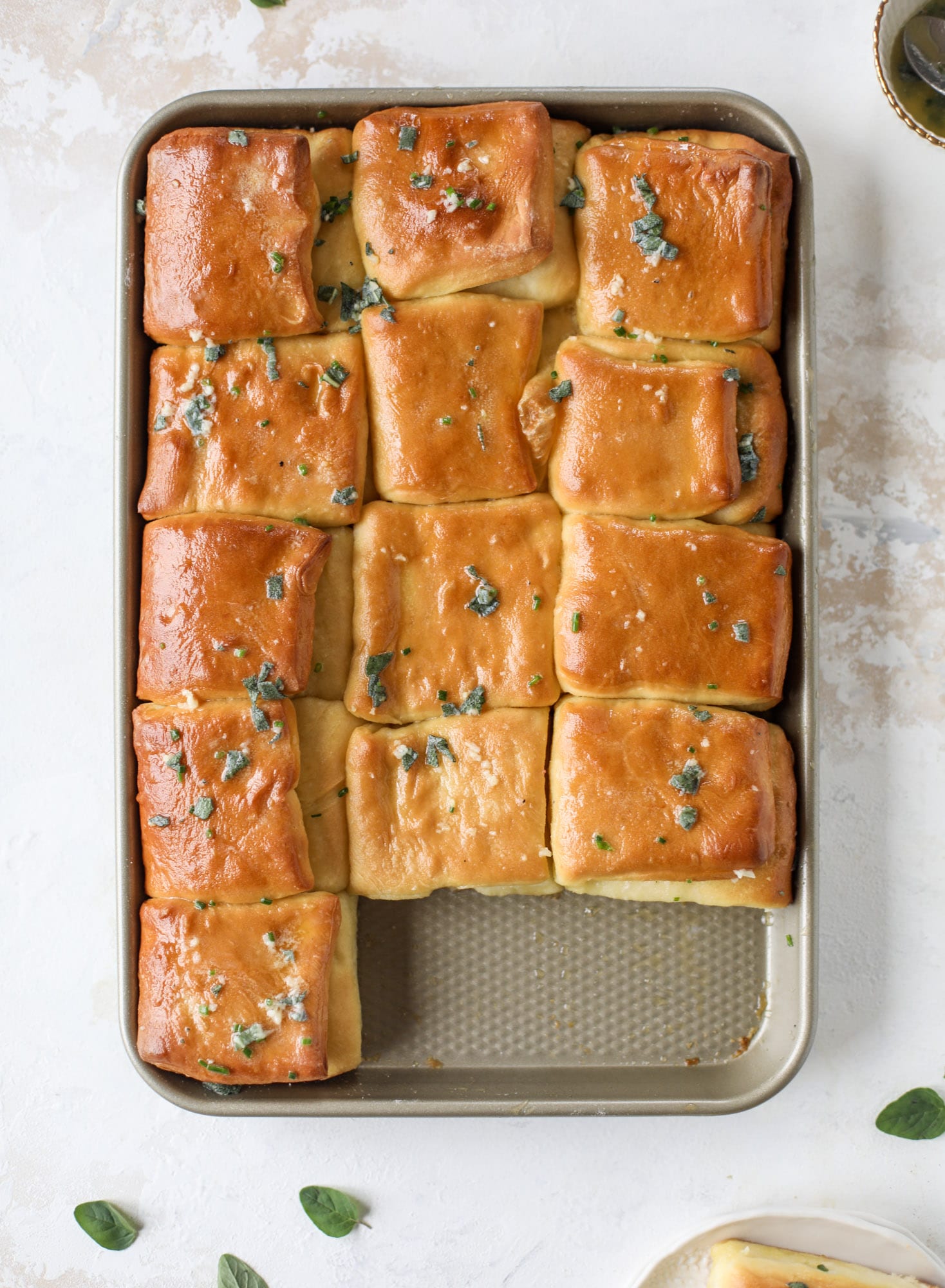 Garlic herb parker house rolls are full of incredibly buttery flavor! They are brushed with a garlic herb butter and are super fluffy, soft and tender. Perfect for Thanksgiving or the holidays and you can make the dough a bit ahead of time! I howsweeteats.com #parkerhouse #rolls