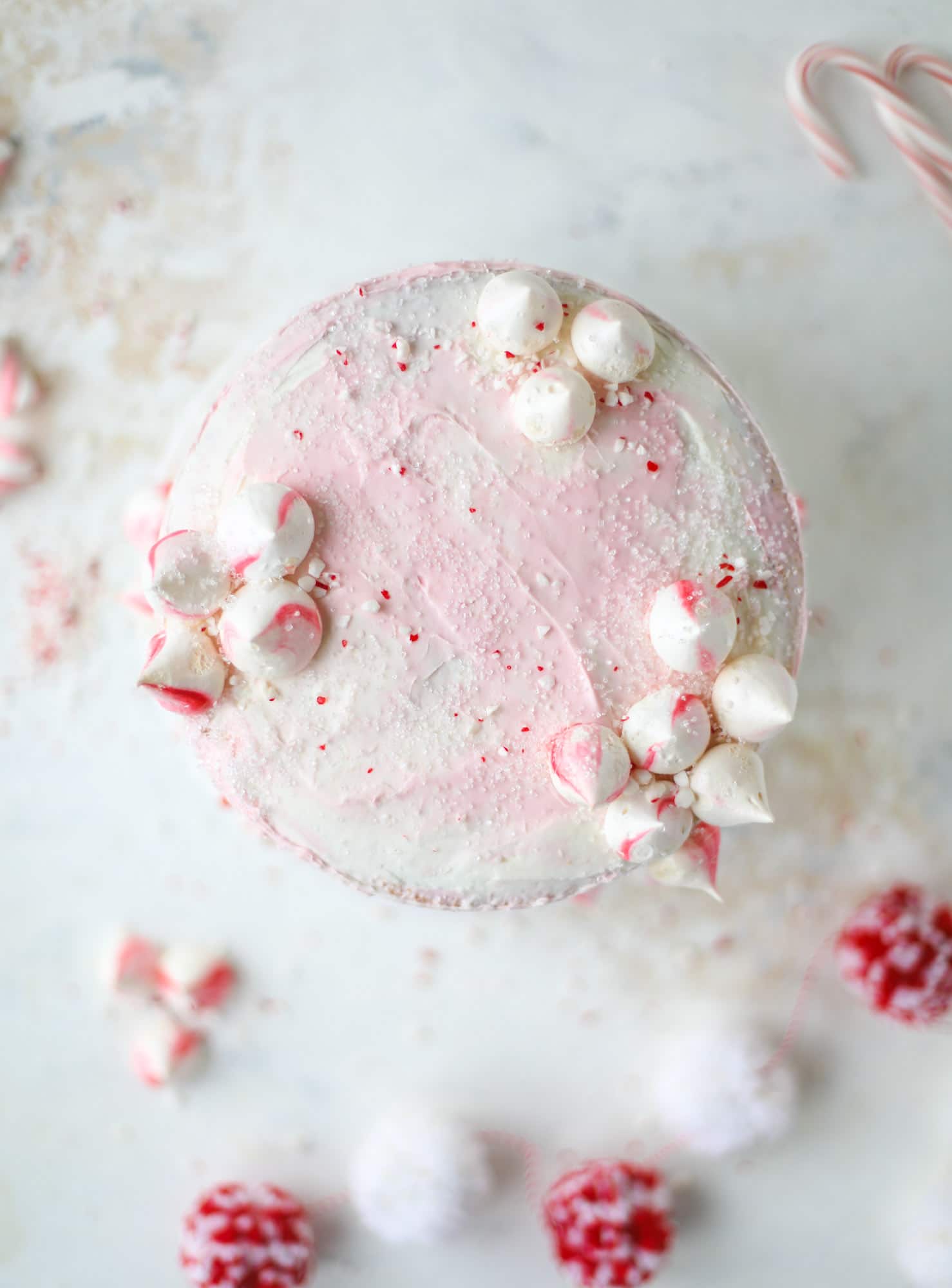 This pink peppermint cake is festive and delicious for the holidays! Layers of vanilla cake frosting with peppermint cream cheese frosting, covered in sparkly sugar and peppermint meringues. Couldn't be cuter! I #pinkpeppermint #cake