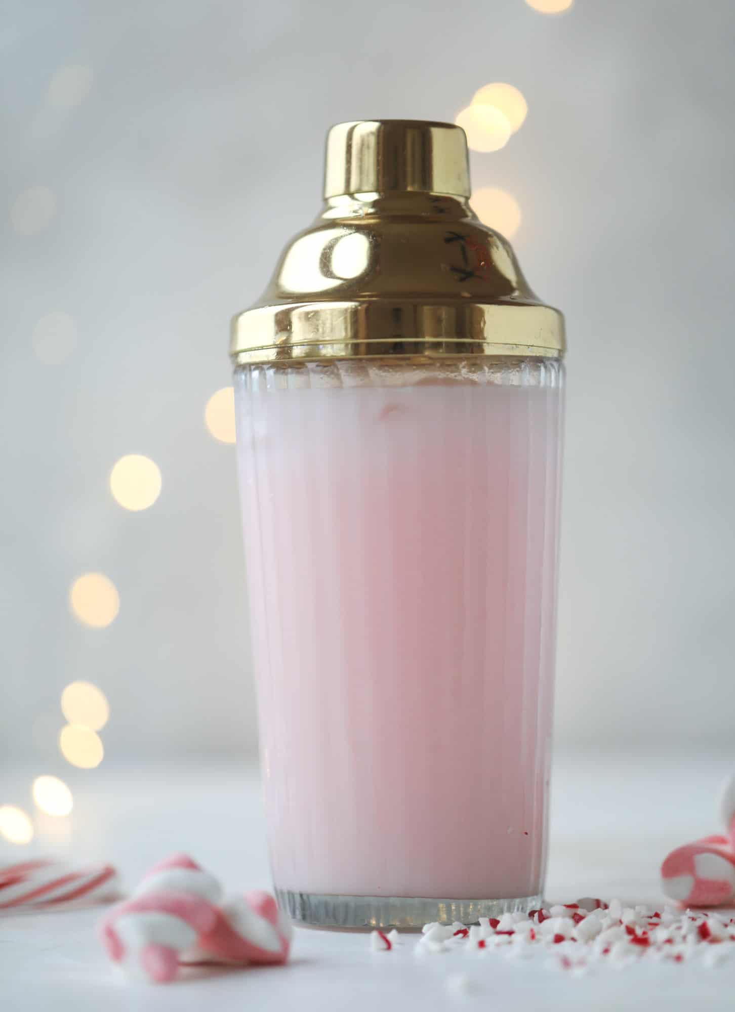 This pink peppermint cocktail is full of holiday cheer! Candy cane vodka, creme de cacao, vanilla and a drop of cream come together to create the perfect iced holiday drink that tastes like a treat! I howsweeteats.com #pinkpeppermint #cocktail