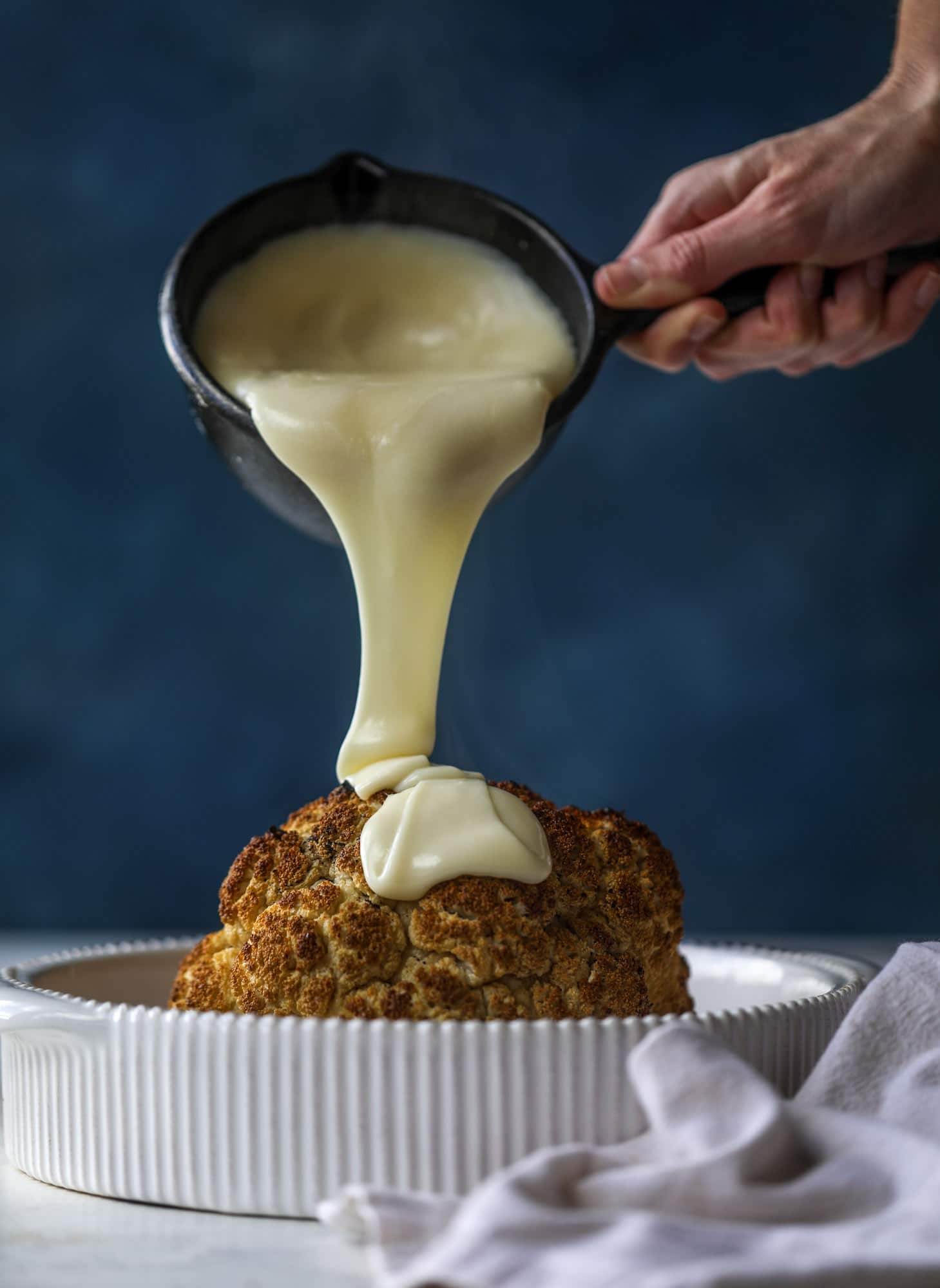 This whole roasted cauliflower fondue is roasted to toasty perfection and then covered in a fondue cheese sauce! Sprinkled with a festive garnish, it's the perfect appetizer or side dish for your dinner party, weeknight meal or movie night! I howsweeteats.com #wholeroasted #cauliflower