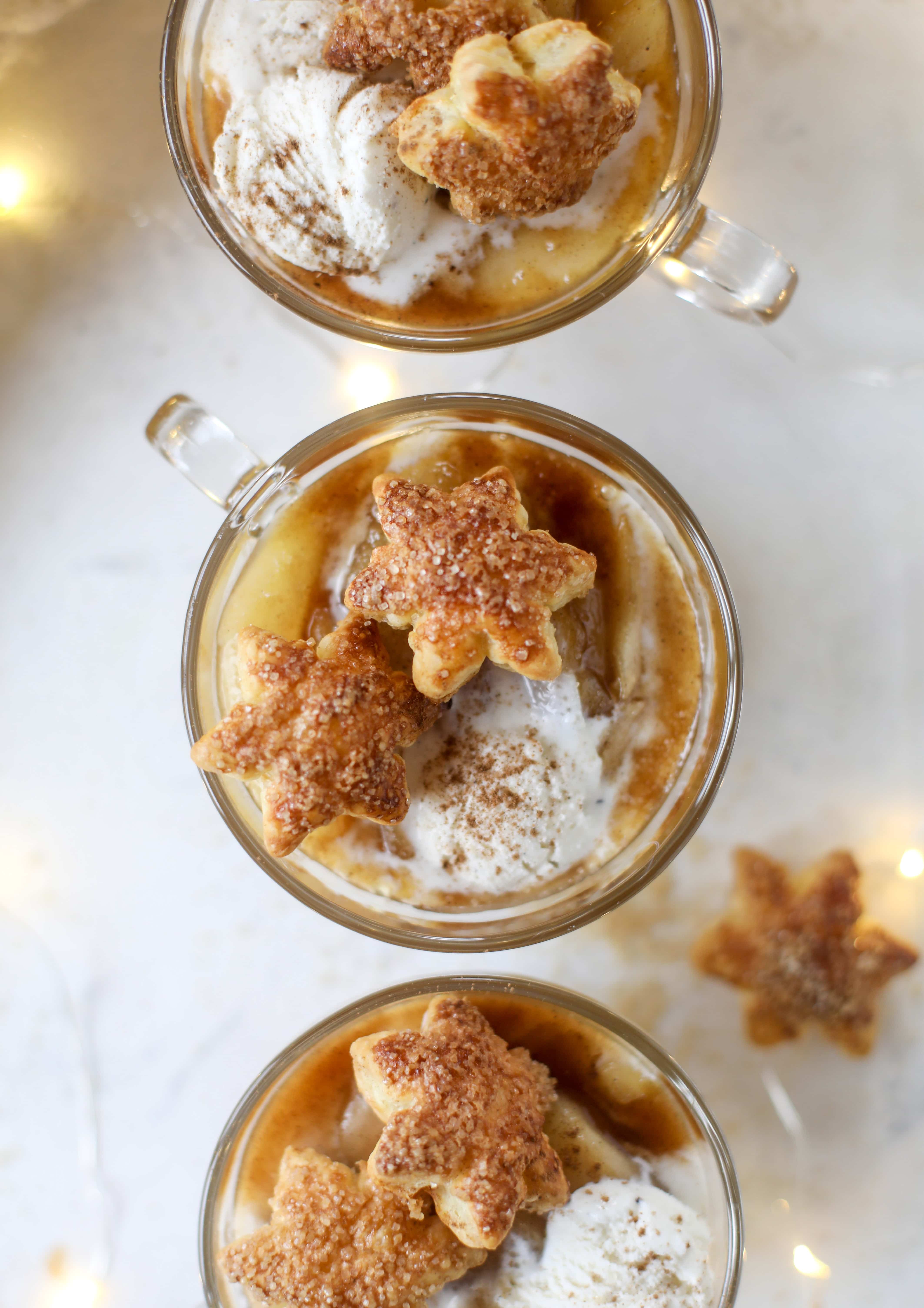 This pear mug pie is the coziest way to enjoy warm, caramelized pears. Topped with vanilla ice cream and the cutest, quick puff pastry stars, these are a great dessert for a dinner party or an easy one to make for yourself on a Saturday night! I howsweeteats.com #pear #mugpie