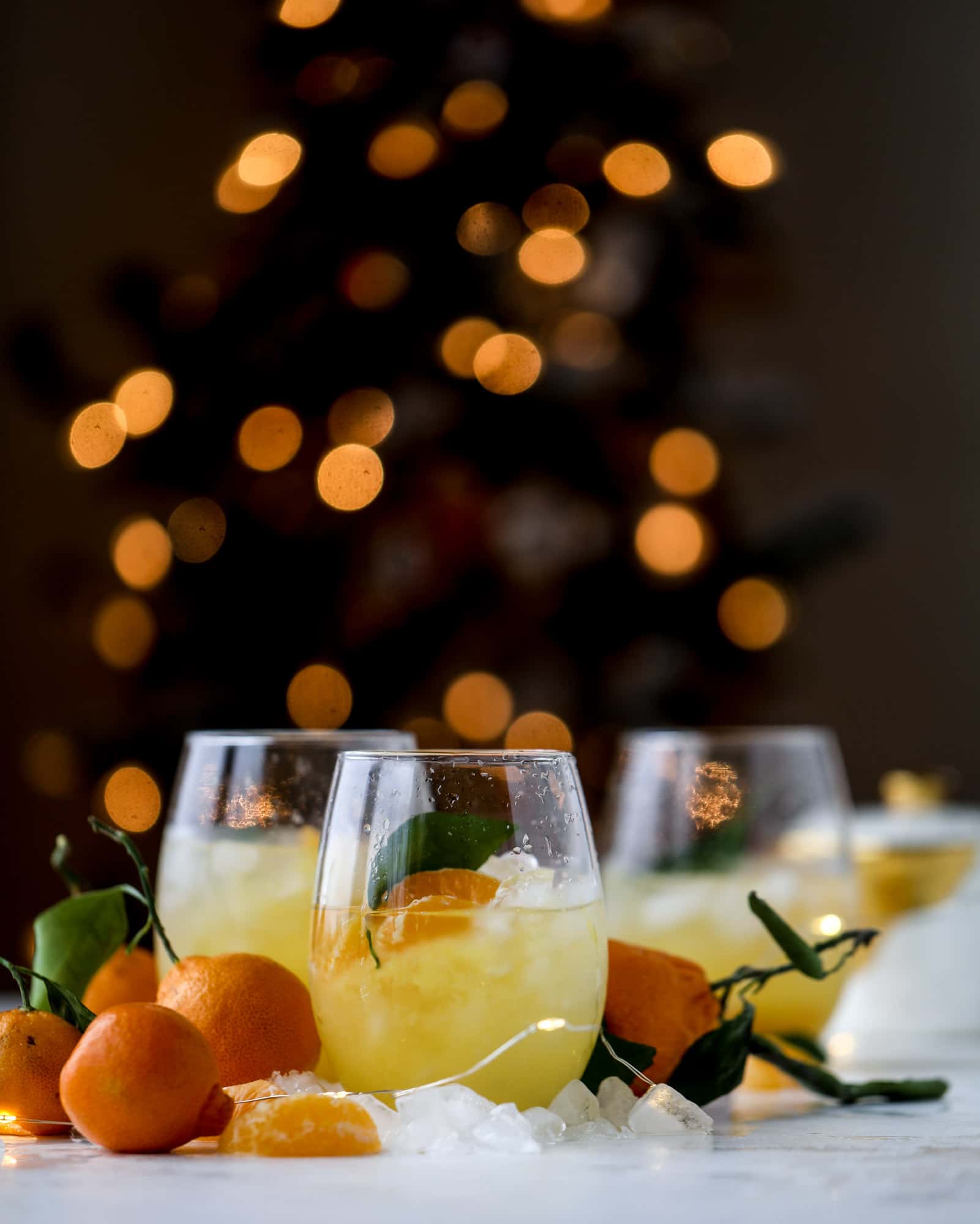 This satsuma cocktail is perfect for the holiday season and winter months when sweet satsumas are in season! This cocktail uses gin or vodka and is topped with champagne and garnished with a few satsuma wedges. Delicious! I howsweeteats.com #satsuma #cocktail