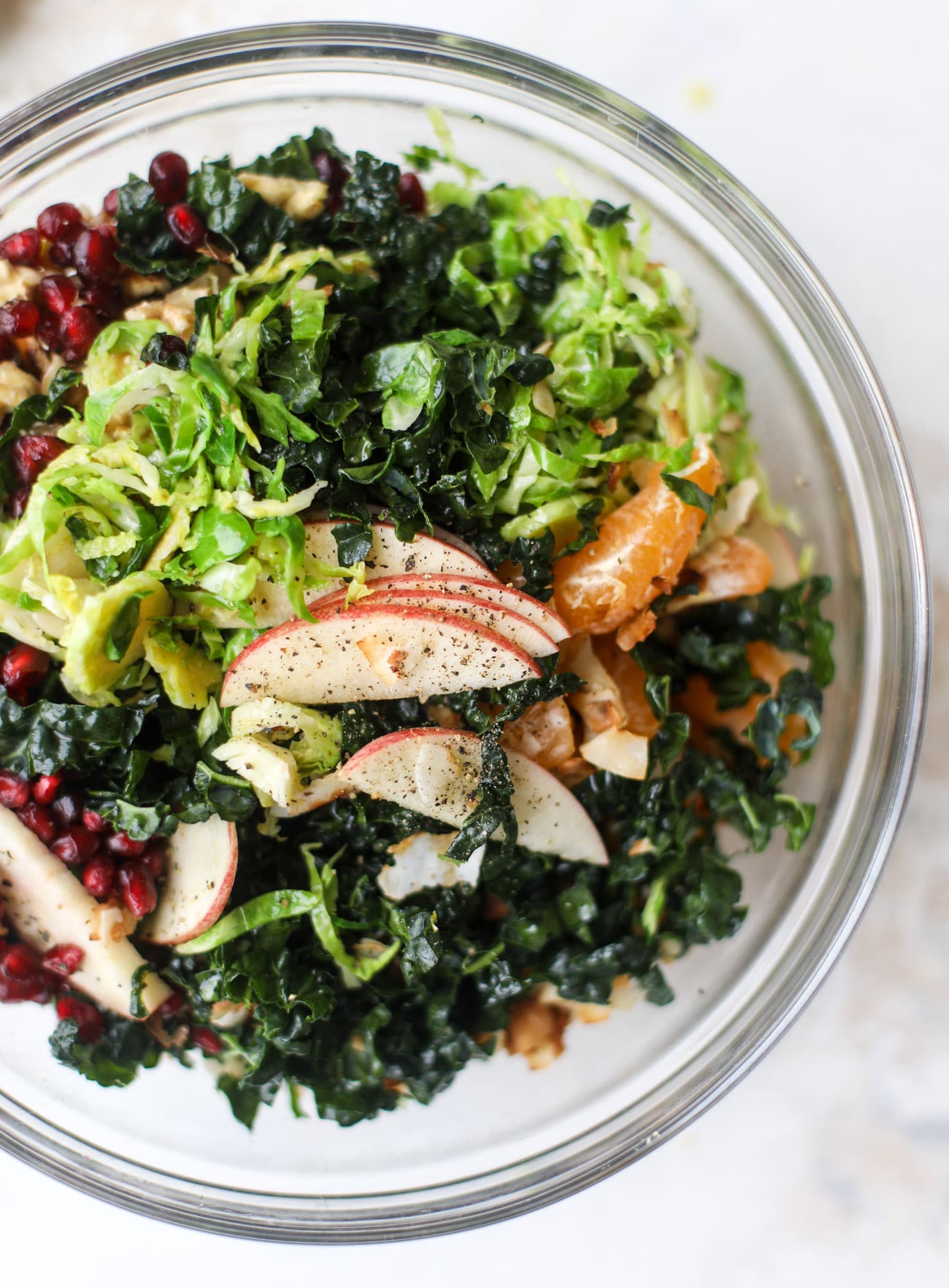This winter crunch salad is loaded with tons of delicious, crunchy seasonal ingredients. A base of brussels sprouts and kale is topped with sliced apples, satsuma wedges, pomegranate arils, toasted walnuts and savory flaked coconut crunch. Delish! I howsweeteats.com #winter #salad