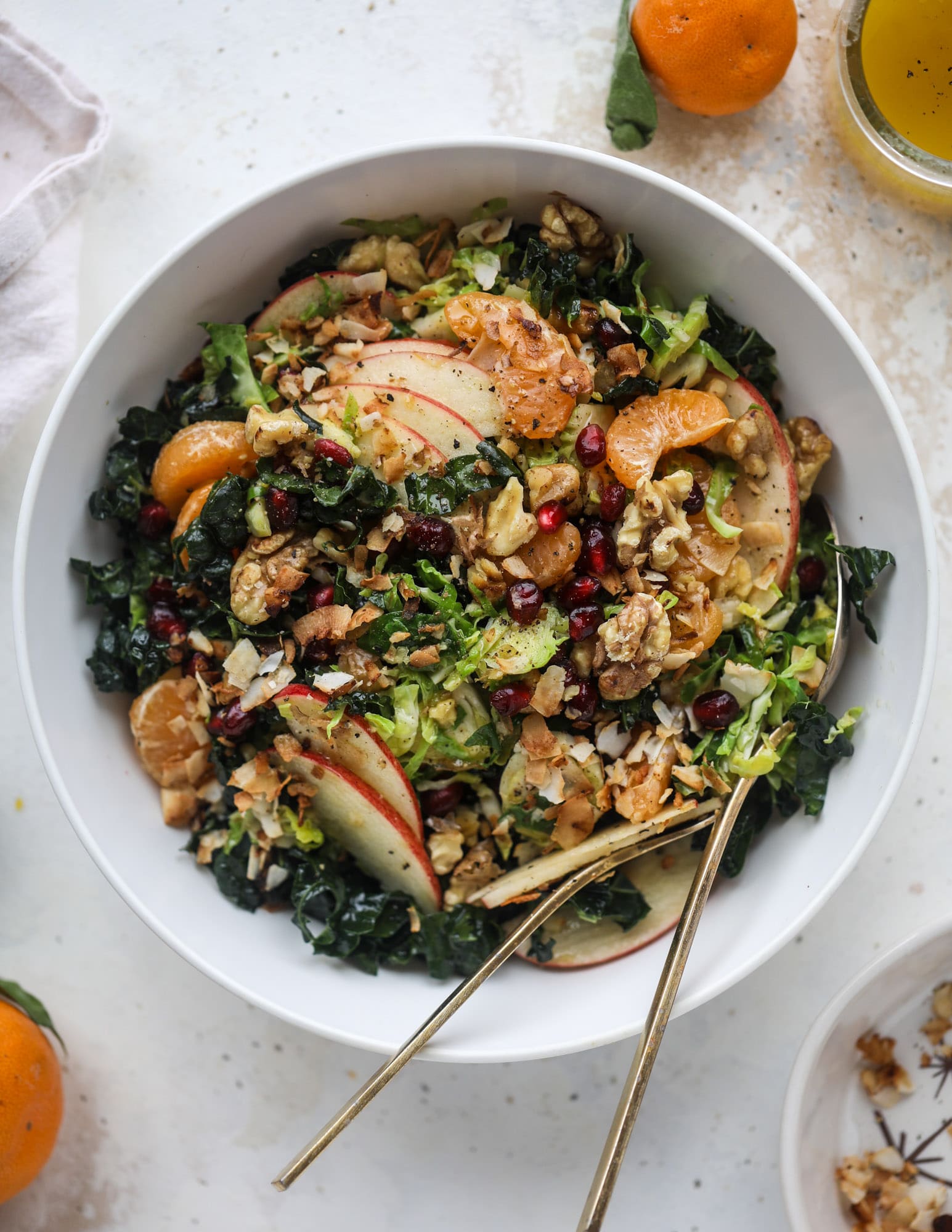 This winter crunch salad is loaded with tons of delicious, crunchy seasonal ingredients. A base of brussels sprouts and kale is topped with sliced apples, satsuma wedges, pomegranate arils, toasted walnuts and savory flaked coconut crunch. Delish! I howsweeteats.com #winter #salad