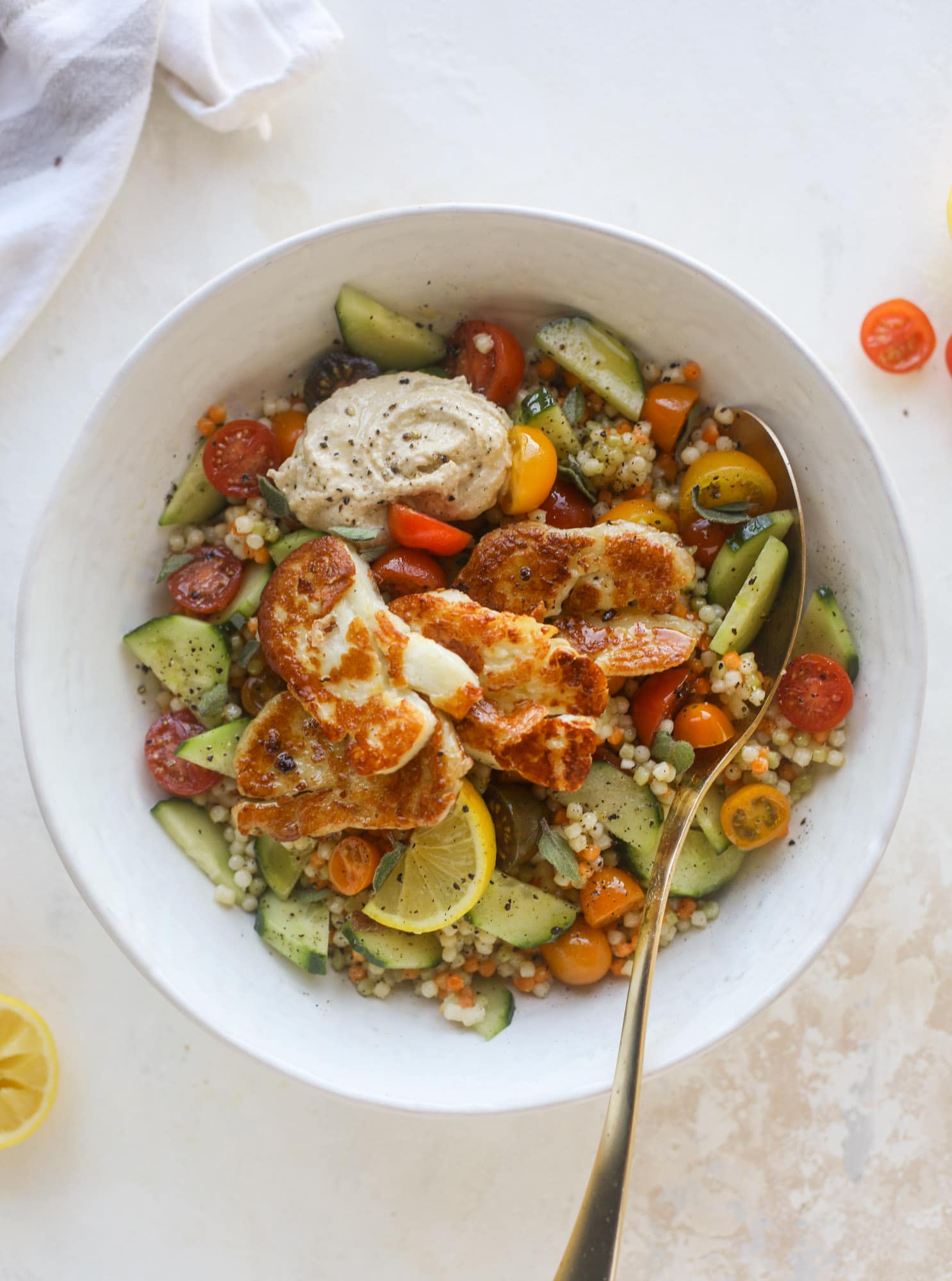 I am obsessed with these haulloumi hummus bowls for lunch or dinner. Couscous, veggies, crispy halloumi cheese and hummus with lots of lemon. Yum! I howsweeteats.com #halloumi #hummus