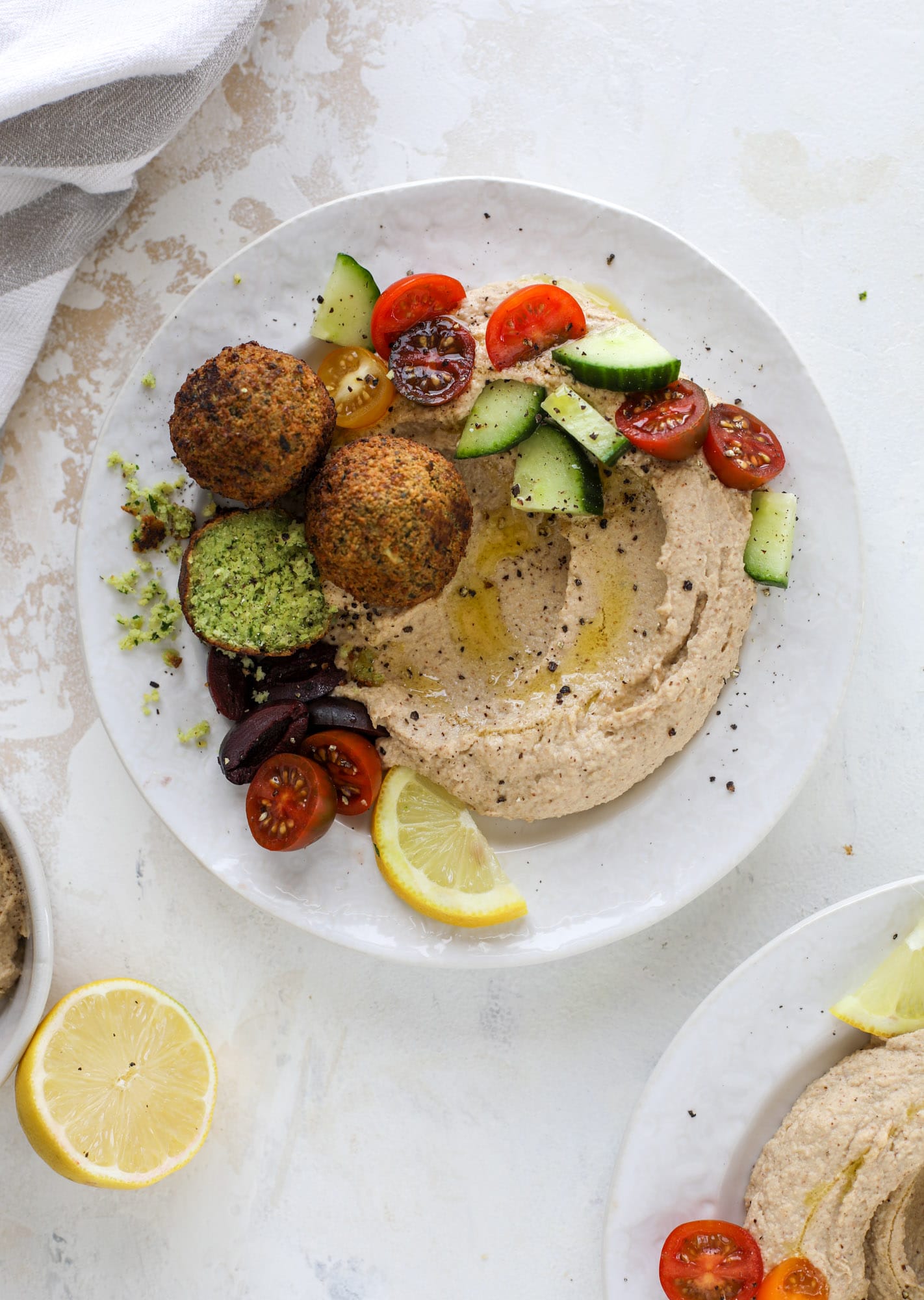 Green goddess falafel is hearty and flavorful, served over the creamiest cauliflower hummus, with tomatoes, olive, cucumbers and feta. Yum! I howsweeteats.com #falafel #cauliflowerhummus