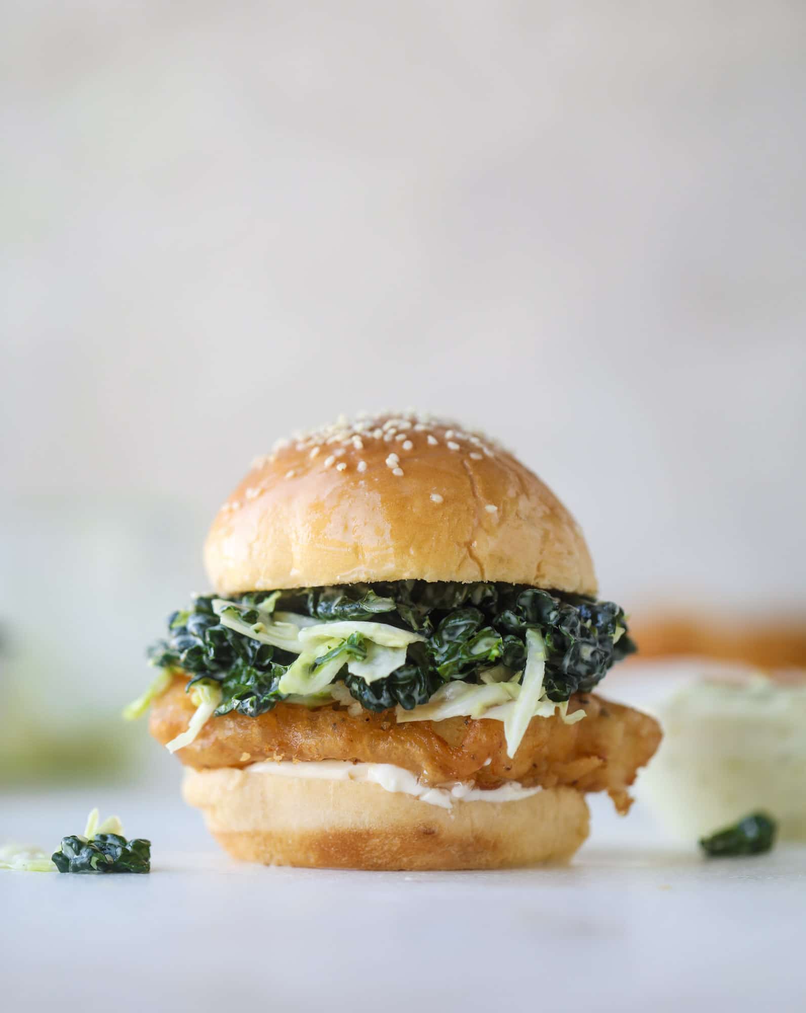 A light and crispy fish sandwich made with a simple beer batter and topped with a hearty, creamy kale cole slaw. Loaded with flavor! I howsweeteats.com #crispyfish #sandwich