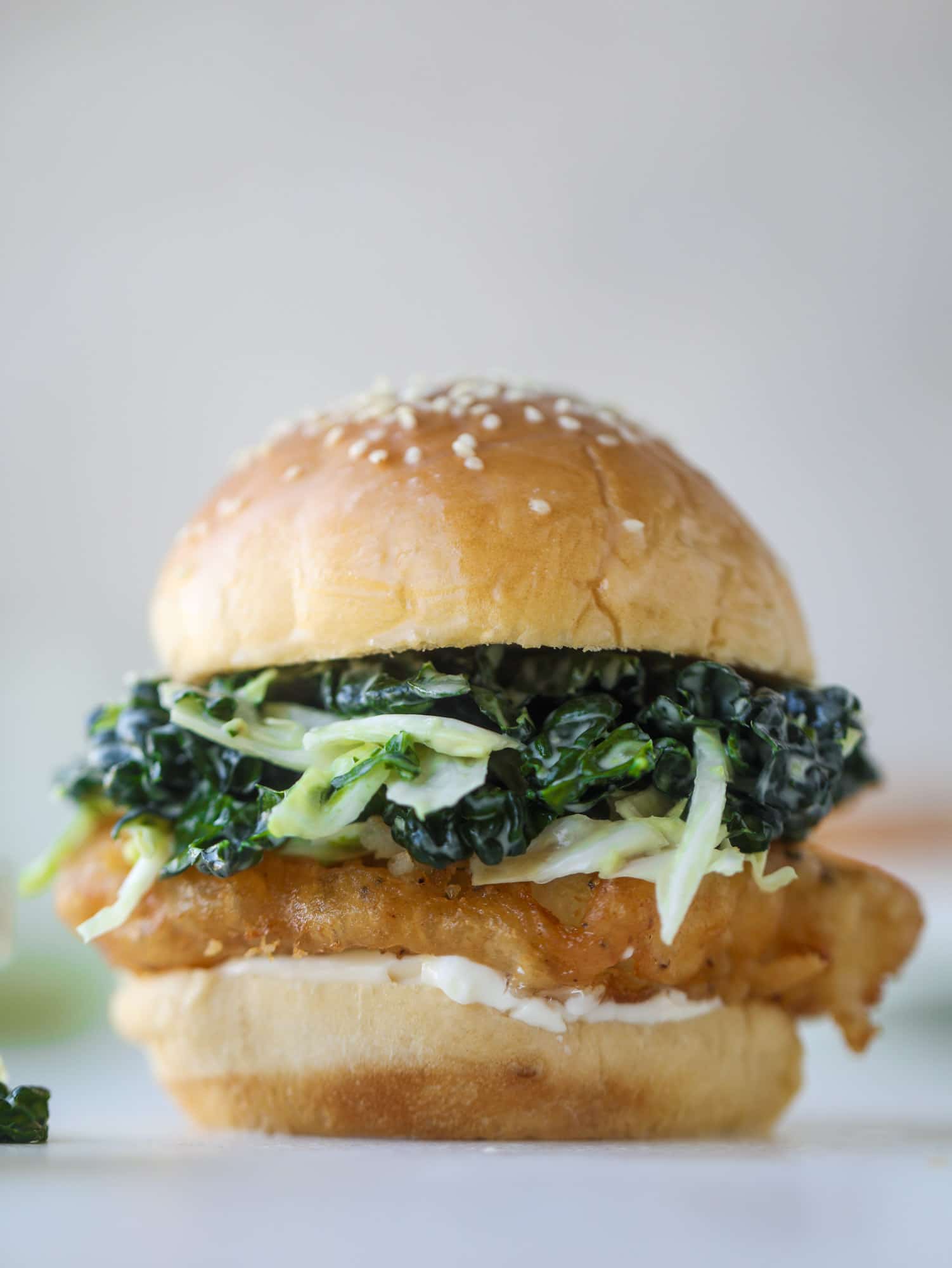 A light and crispy fish sandwich made with a simple beer batter and topped with a hearty, creamy kale cole slaw. Loaded with flavor! I howsweeteats.com #crispyfish #sandwich