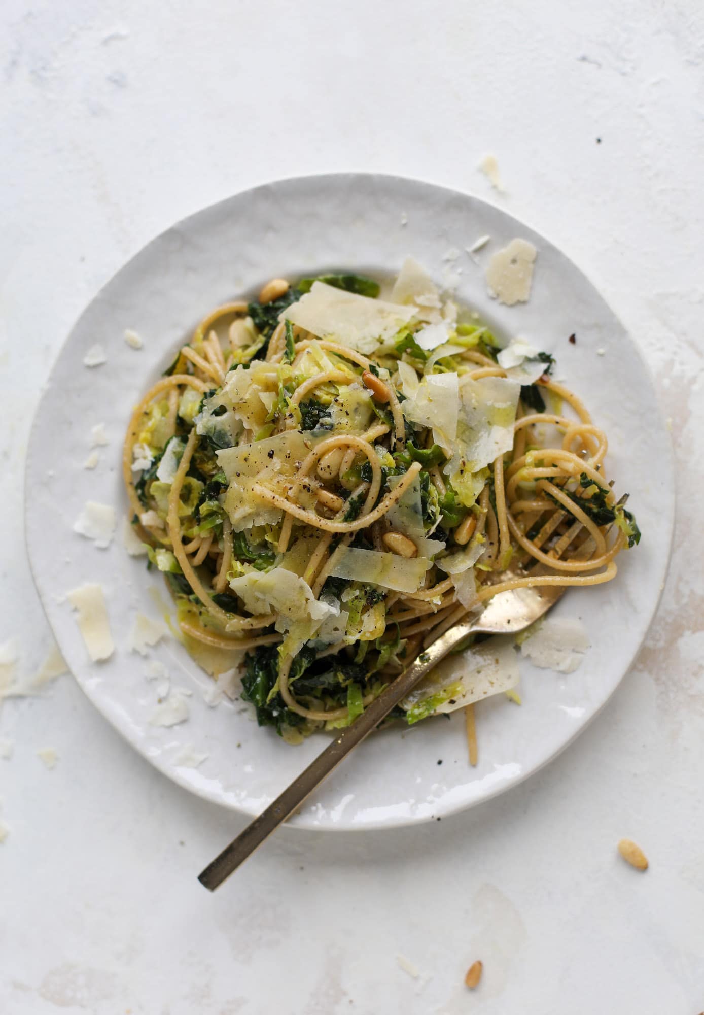 This brussels spaghetti with kale, parmesan and pine nuts is a super flavorful, quick and easy weeknight meal. You can add in a protein if you wish! I howsweeteats.com #brussels #spaghetti