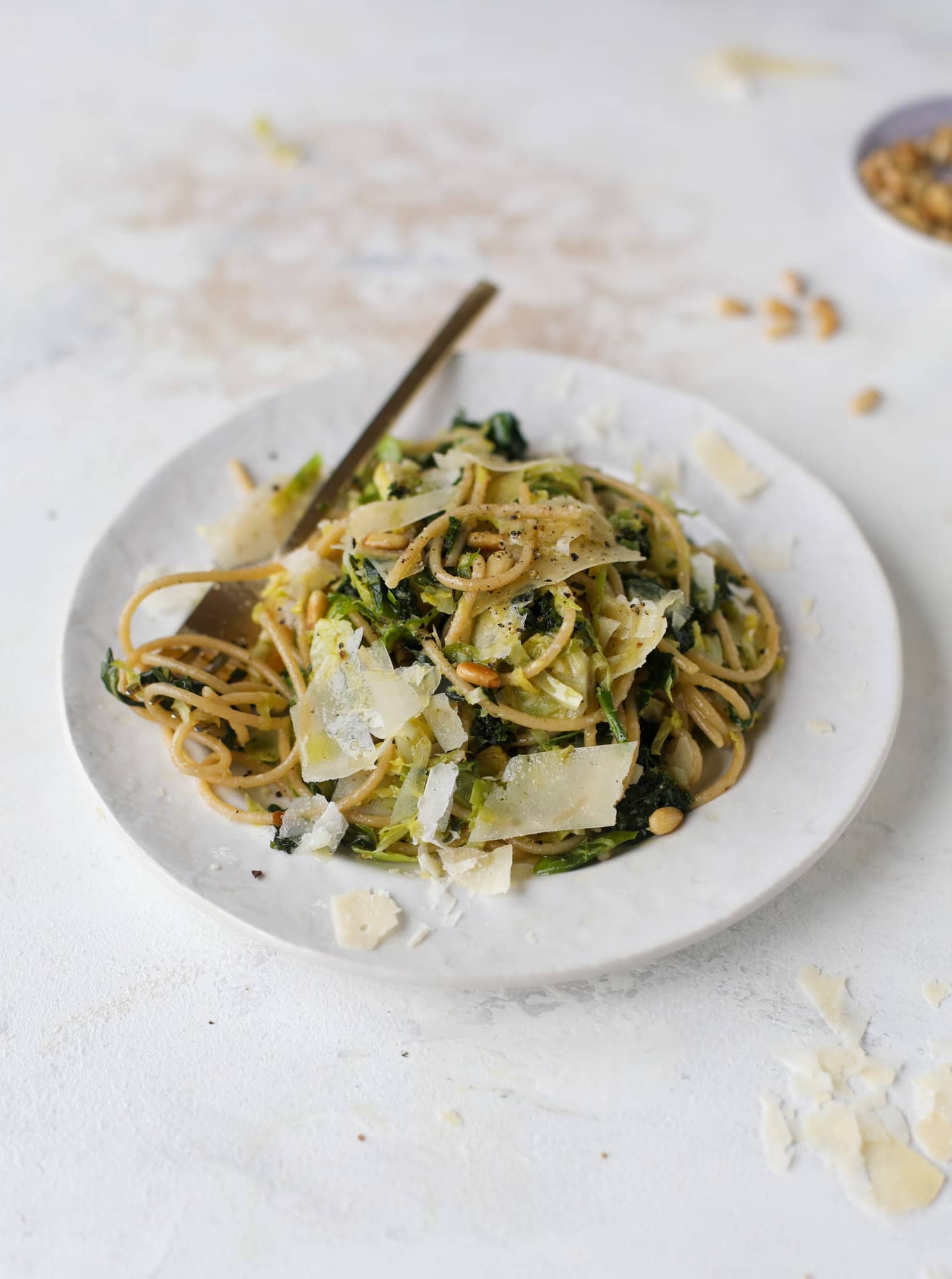 This brussels spaghetti with kale, parmesan and pine nuts is a super flavorful, quick and easy weeknight meal. You can add in a protein if you wish! I howsweeteats.com #brussels #spaghetti