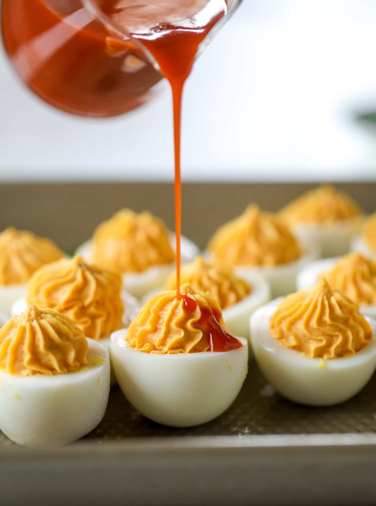 drizzling buffalo wing sauce on deviled eggs