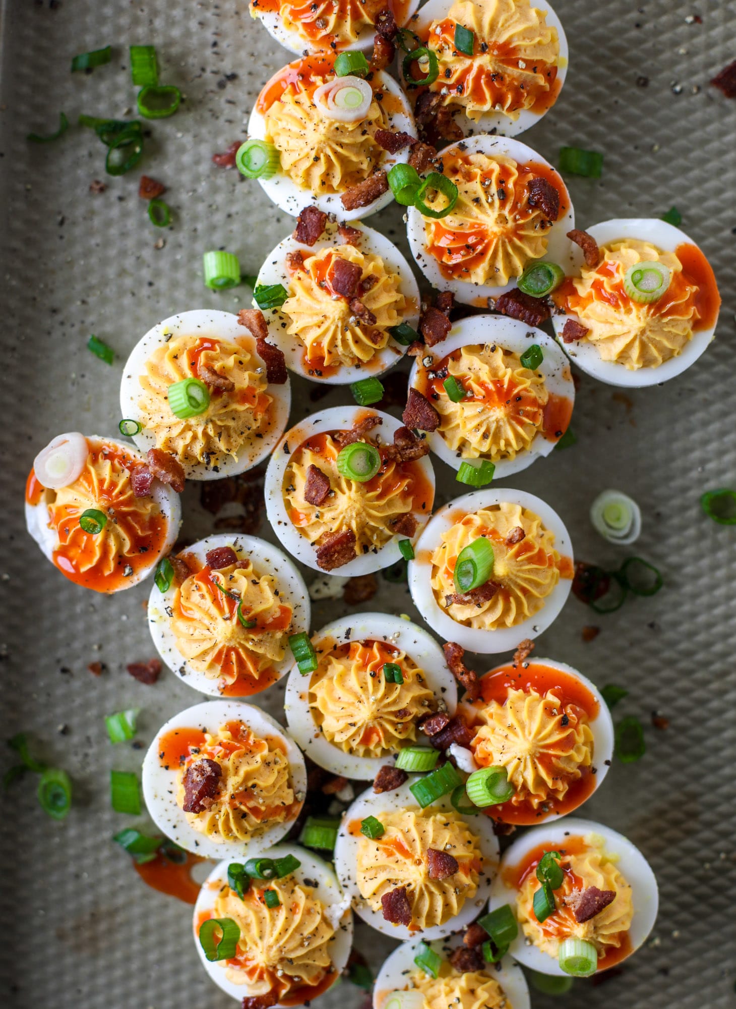 Buffalo deviled eggs are kicked-up deviled eggs! Made with goat cheese filling and served with buffalo wing sauce, crispy bacon and sliced scallions. I howsweeteats.com #deviledeggs #buffalo