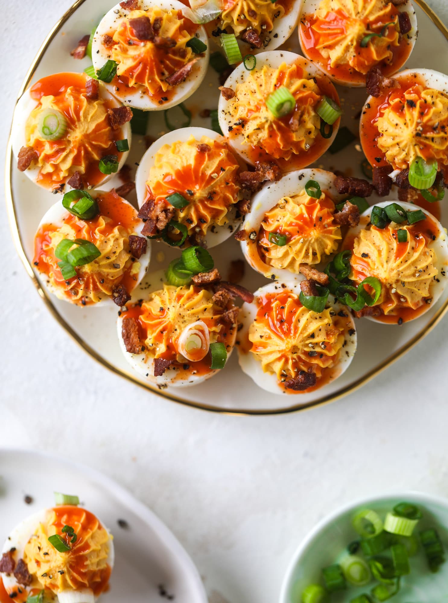 Buffalo deviled eggs are kicked-up deviled eggs! Made with goat cheese filling and served with buffalo wing sauce, crispy bacon and sliced scallions. I howsweeteats.com #deviledeggs #buffalo