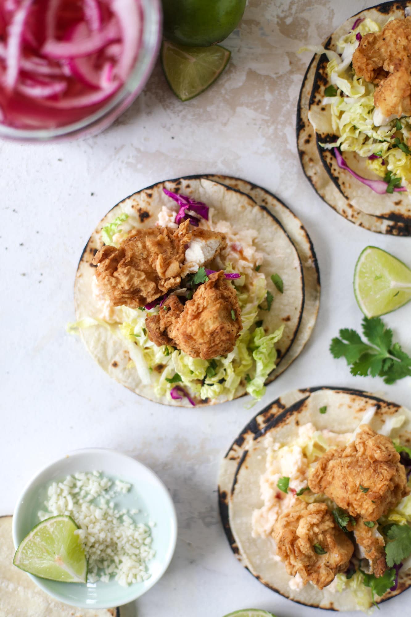 Taking crispy chicken tacos to the next level by wrapping them in a warm tortilla with gouda pimento cheese, lime cabbage and pickled onions!