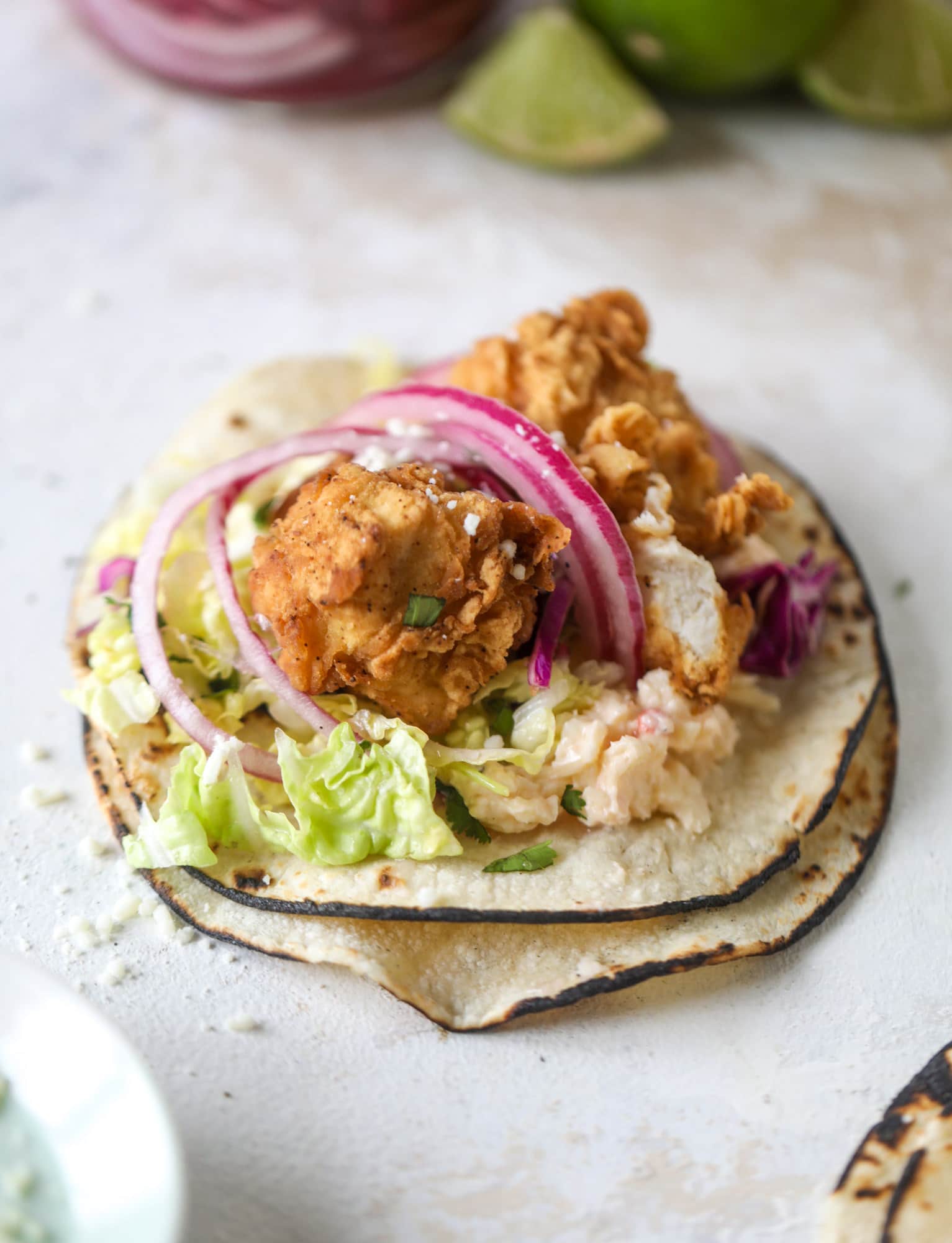 Taking crispy chicken tacos to the next level by wrapping them in a warm tortilla with gouda pimento cheese, lime cabbage and pickled onions!