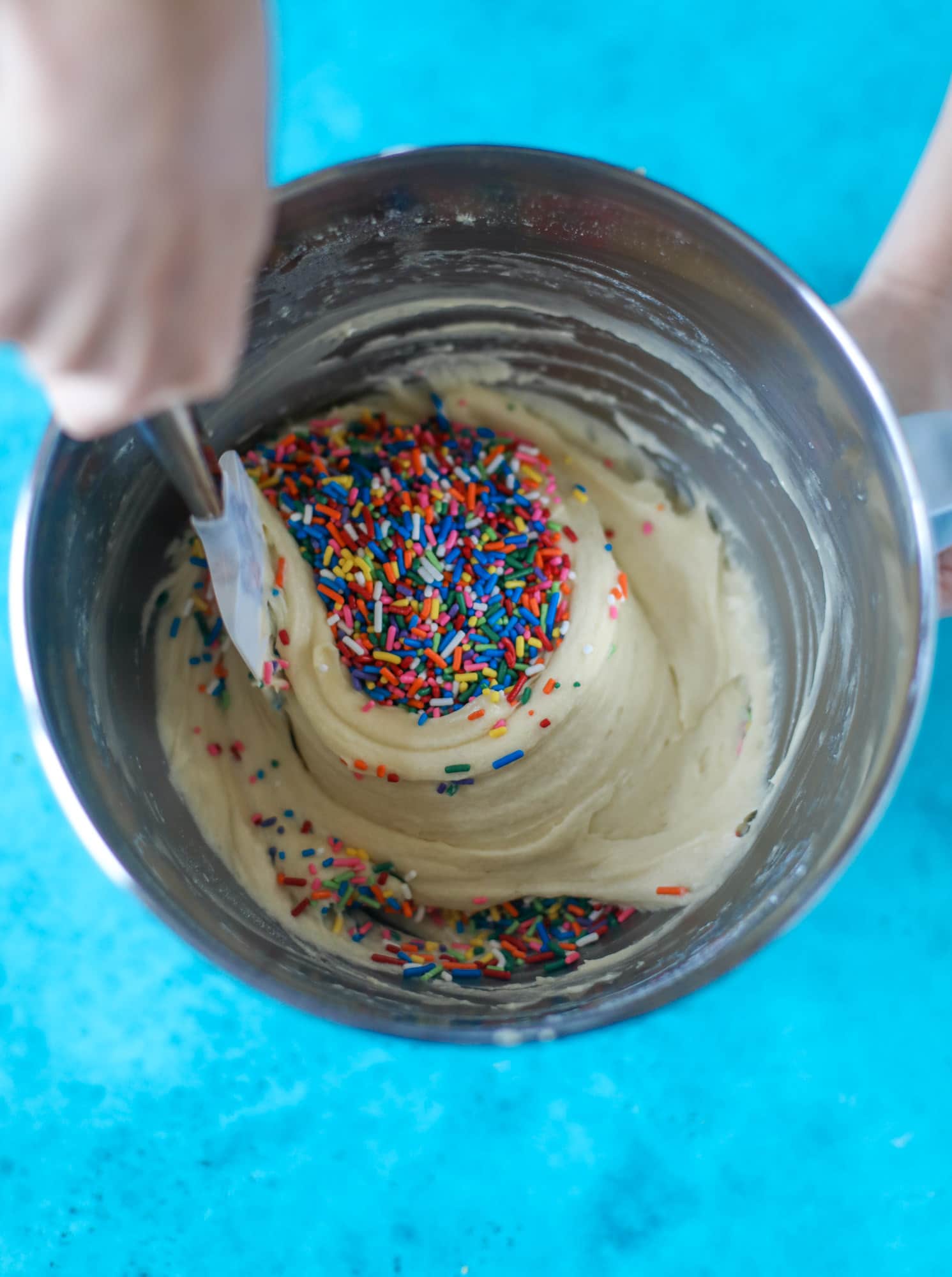 stirring rainbow sprinkles into cake batter