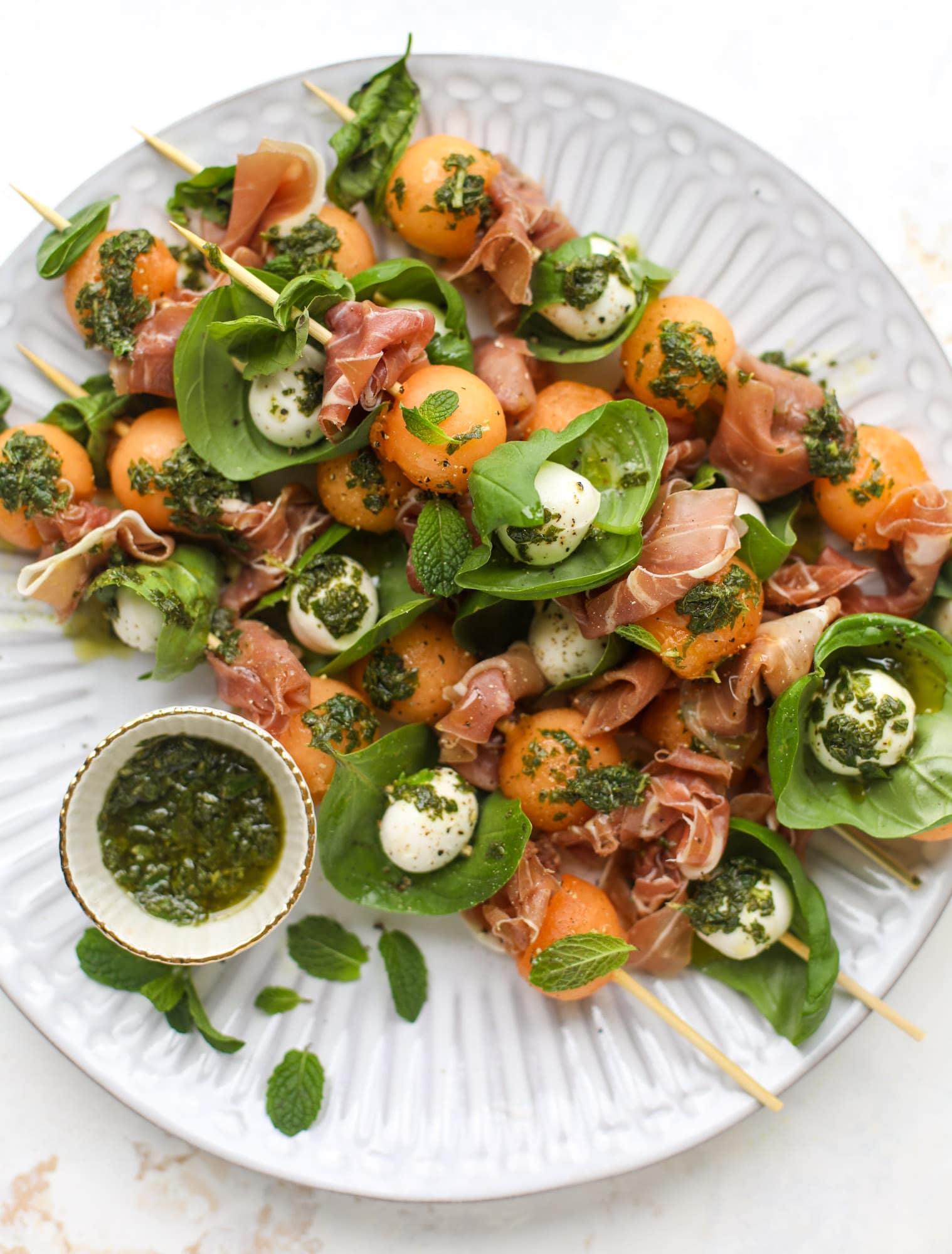 These cantaloupe prosciutto skewers are the perfect cantoloupe caprese snack! Salty prosciutto, sweet melon and fresh mozzarella drizzled with mint pesto!