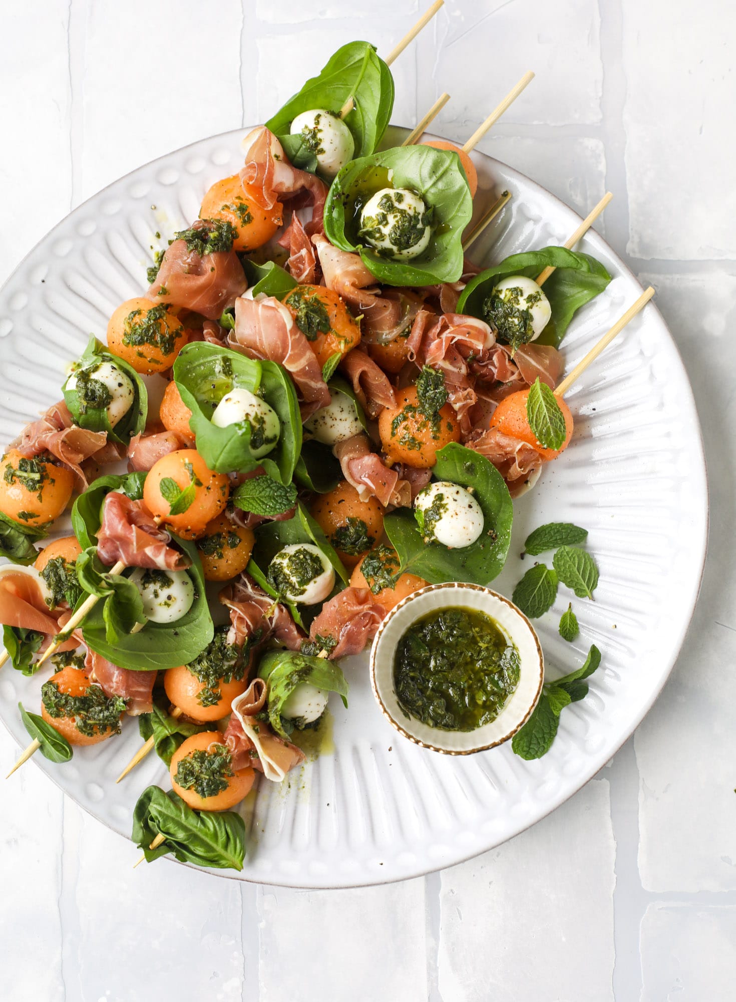 These cantaloupe prosciutto skewers are the perfect cantoloupe caprese snack! Salty prosciutto, sweet melon and fresh mozzarella drizzled with mint pesto!