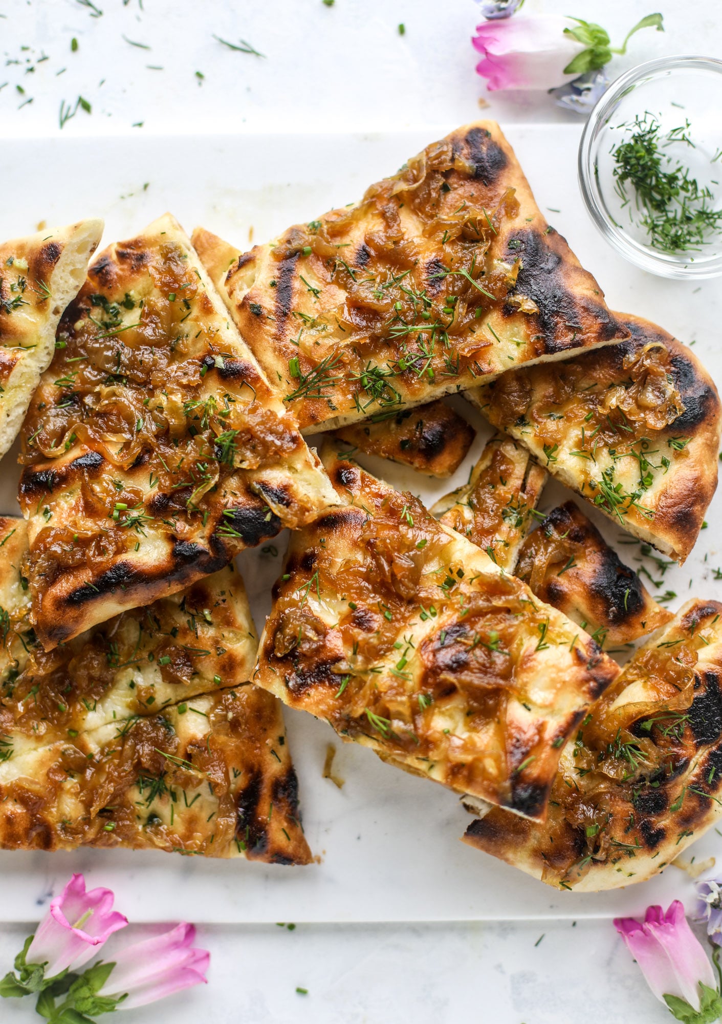 Grilled focaccia bread is such a treat! Topped with puddles of garlic butter, fresh chopped herbs and golden, caramelized onions, it's a slice of heaven.