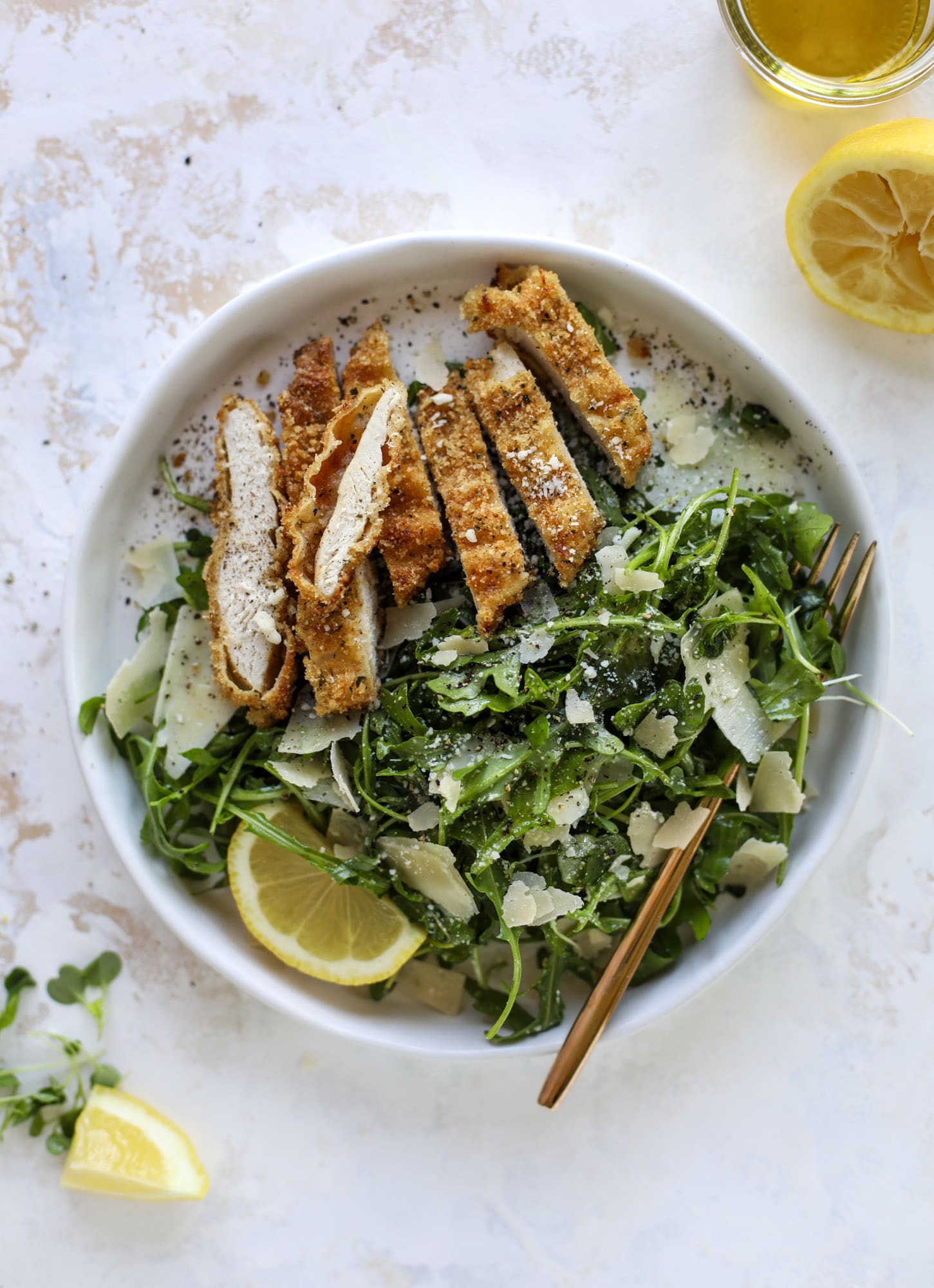 Crispy baked parmesan chicken is so super easy and delicious! It's an amazing weeknight meal served with a lemon arugula salad. Delish!