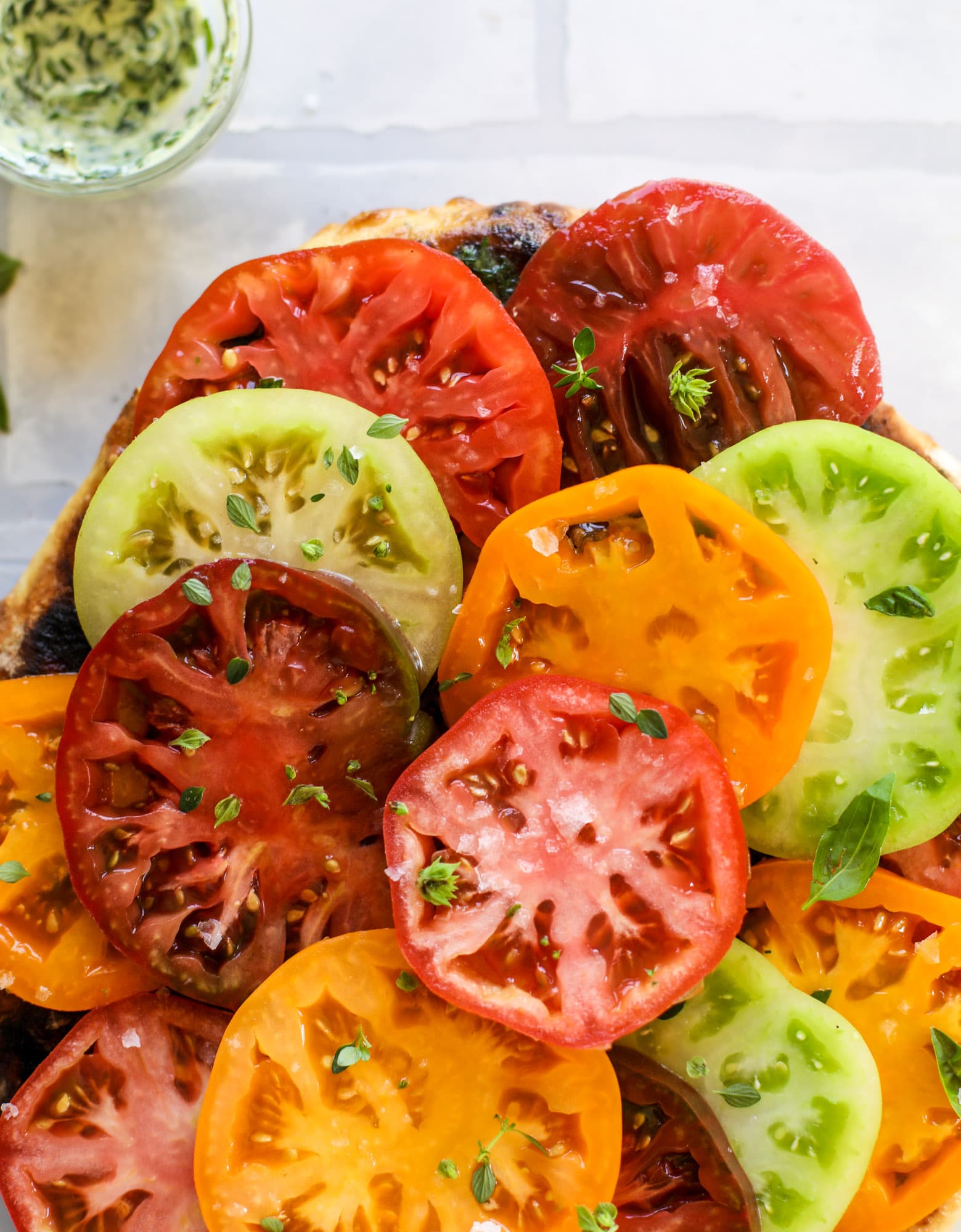 This heirloom tomato pizza starts with a grilled garlic herb butter crust! Melty herb butter and sliced fresh tomatoes top it off for a delicious bite!