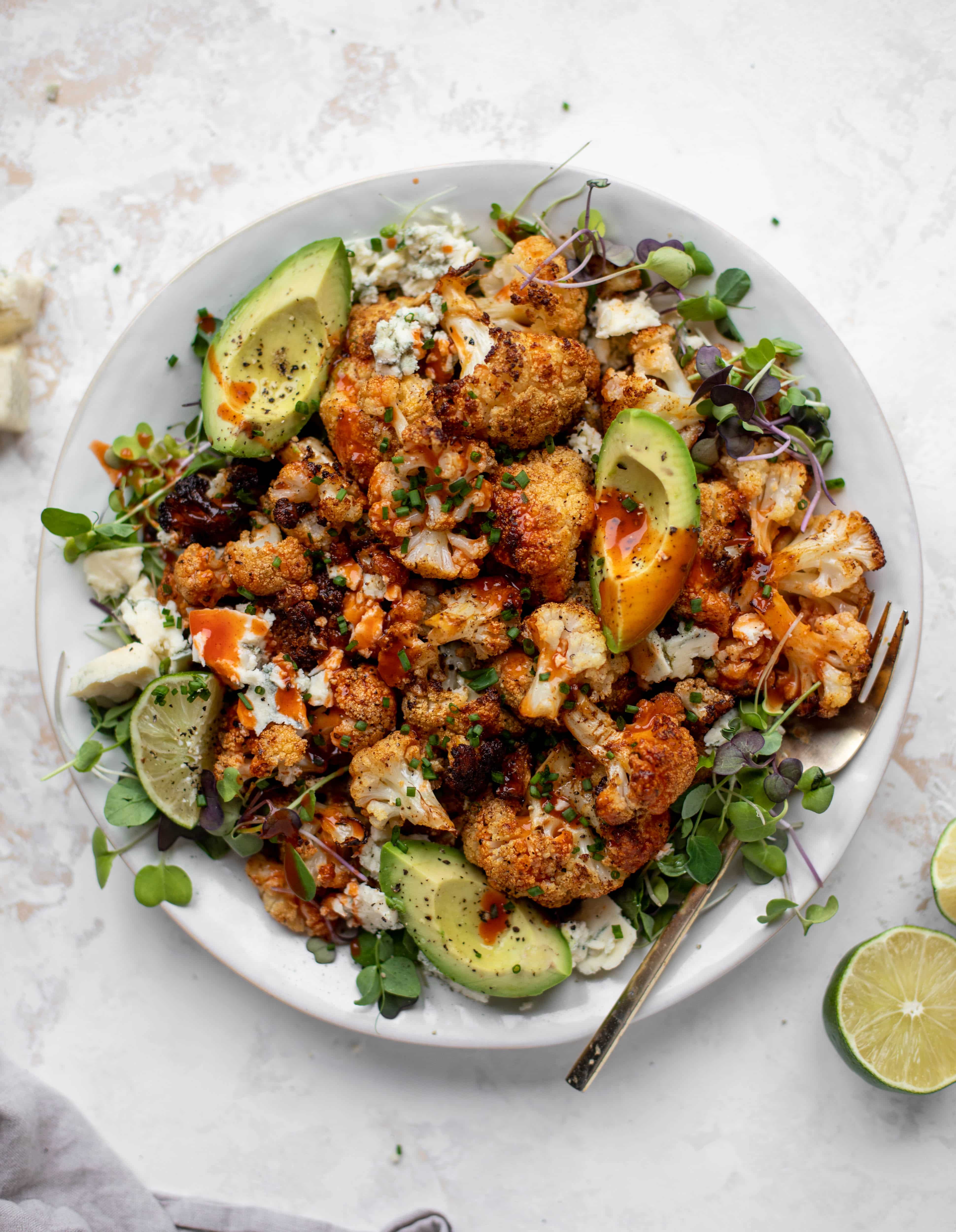 This crispy buffalo cauliflower is loaded with flavor! Serve with avocado and smoked blue cheese - you will want to eat this everyday!