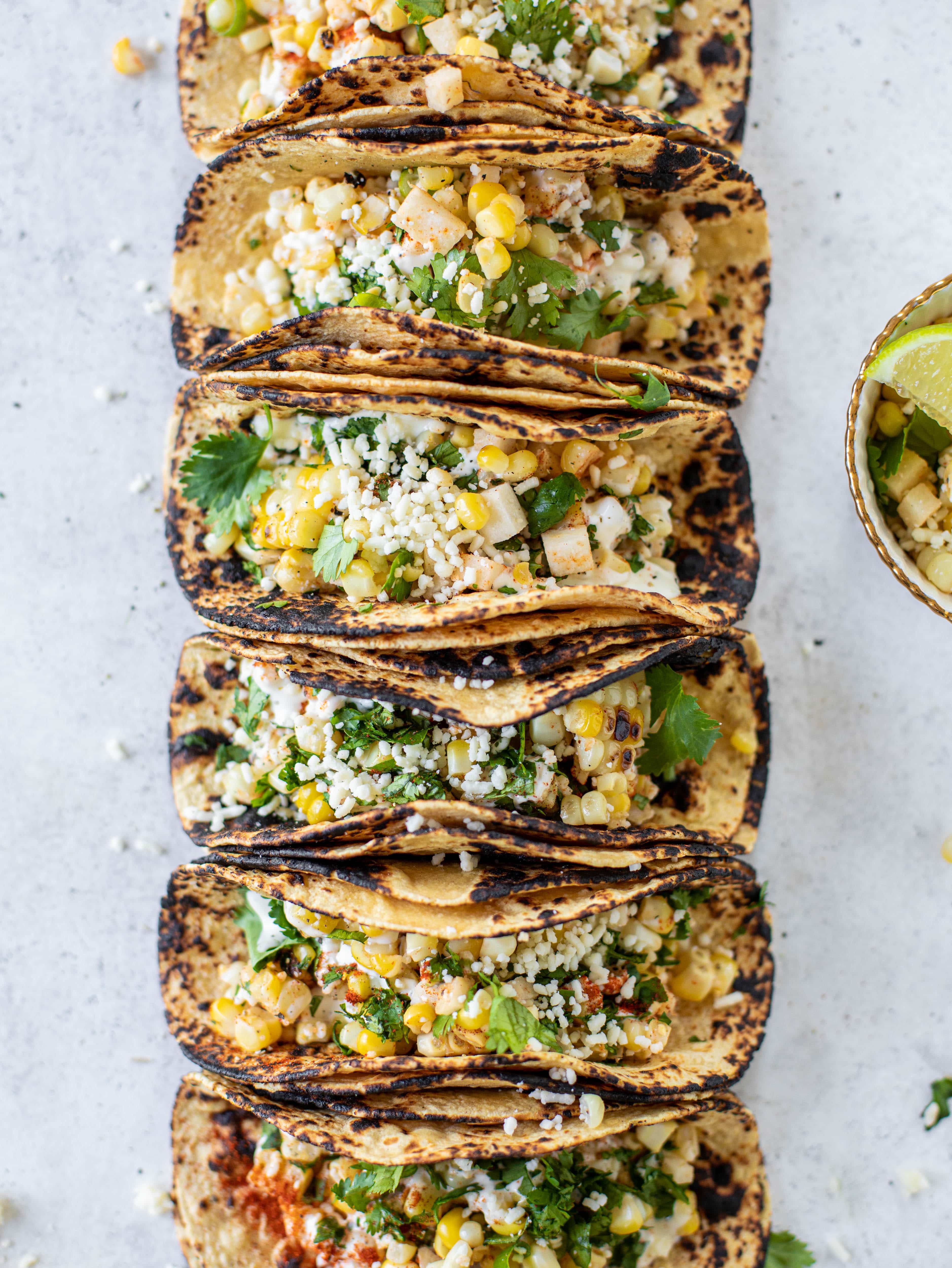 These street corn tacos are filled with a jicama corn salad and drizzled with garlic mayo. This little taco packs a major flavor punch.