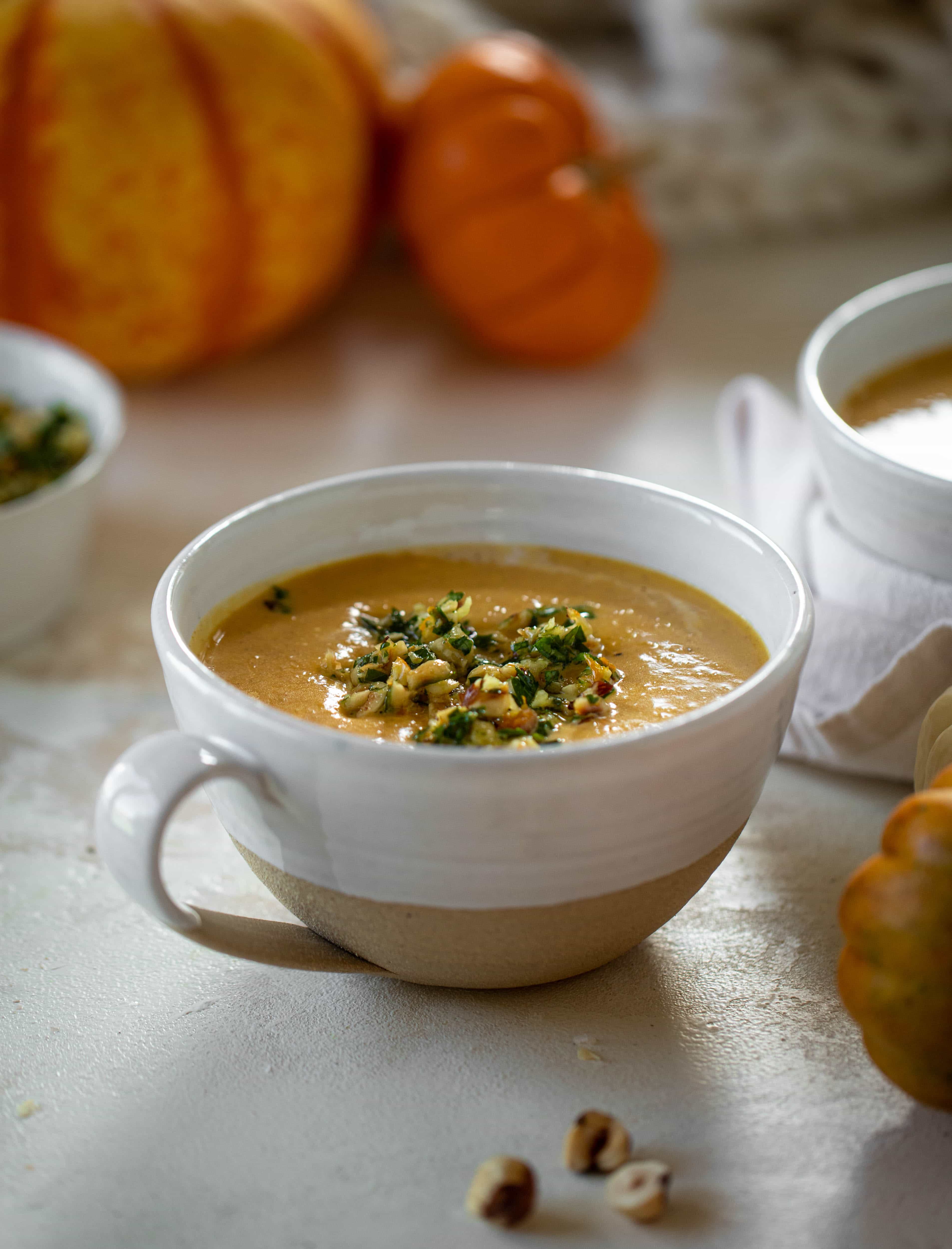 This pumpkin cream soup is silky smooth and delicious, then topped with a roasted hazelnut gremolata for extra flavor and crunch!
